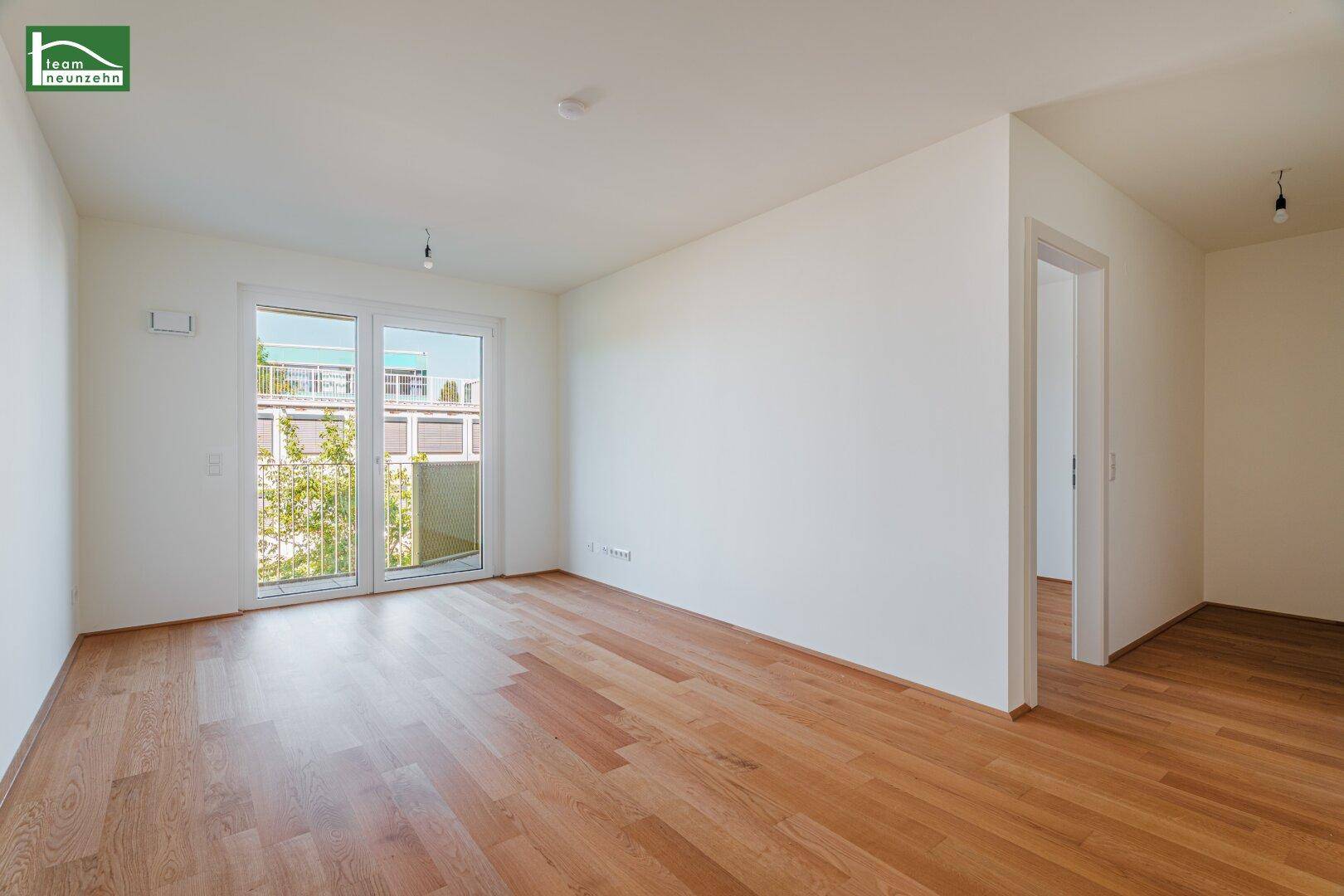 Helles, unmöbliertes Zimmer mit Holzboden und Zugang zu einem Balkon, ideal für Wohn- oder Schlafbereich.