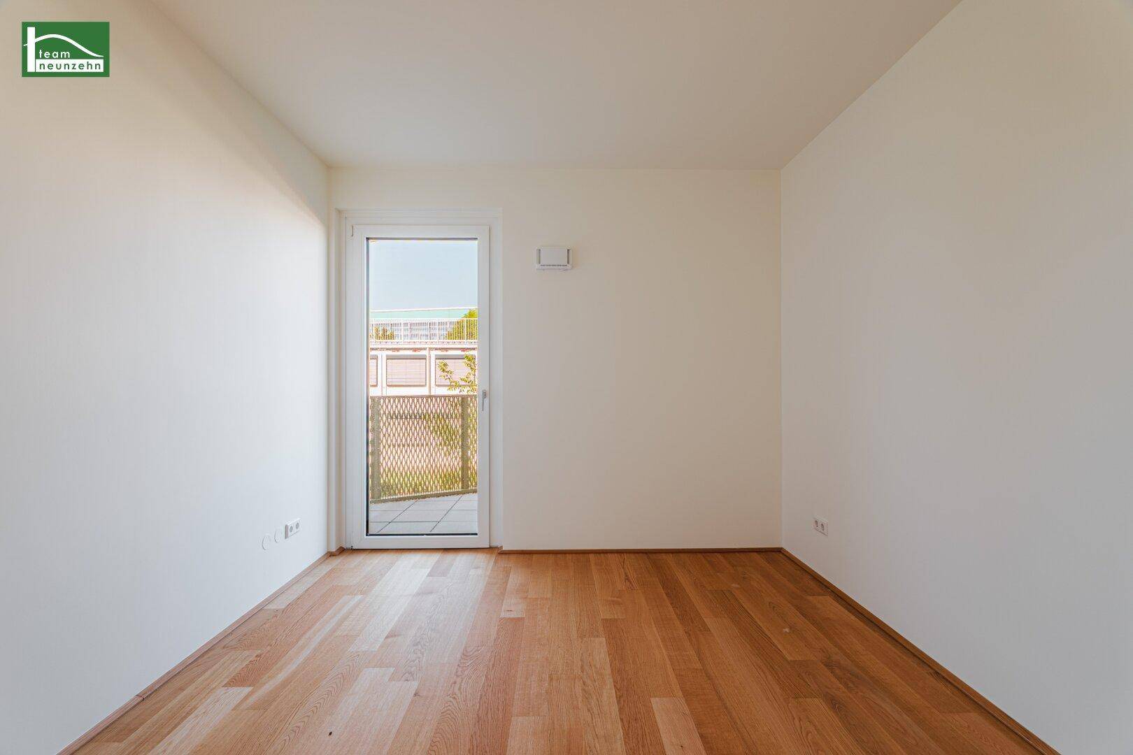 Unmöbliertes Zimmer mit Holzboden und Zugang zu einem kleinen Balkon, vielseitig nutzbar.