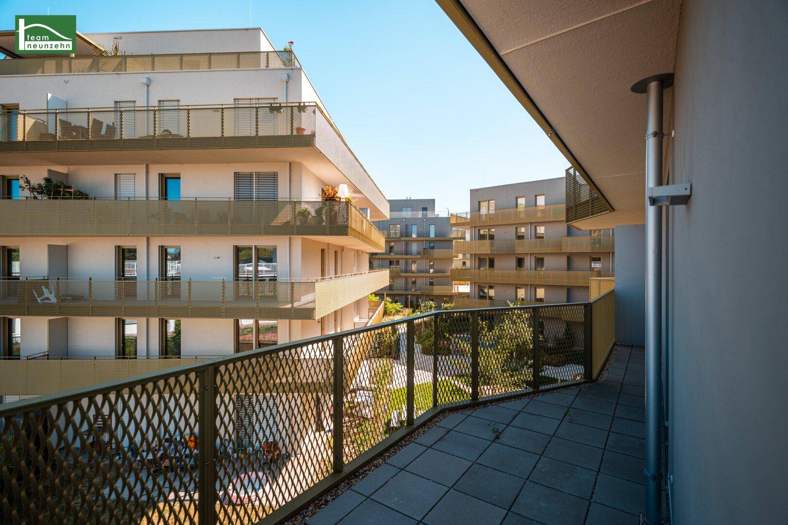 Großer Eckbalkon mit Gittergeländer und Blick auf die umliegenden modernen Gebäude.