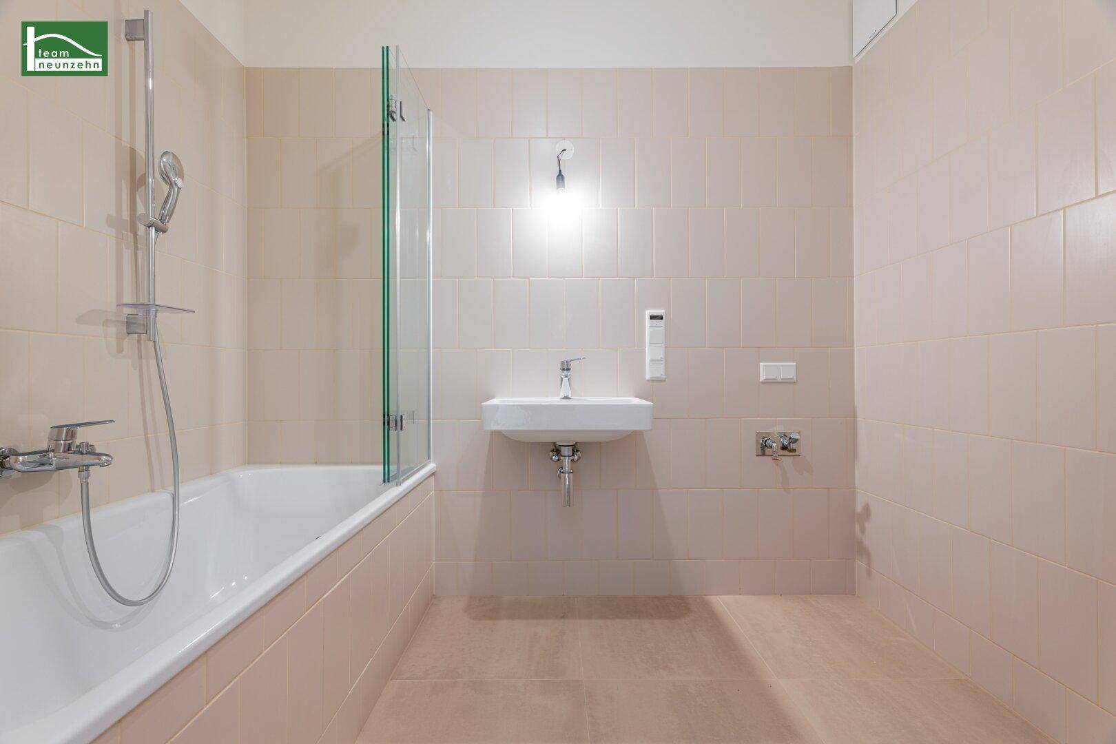 Modernes Badezimmer mit Badewanne, Duschwand und einem einzelnen Waschbecken.
