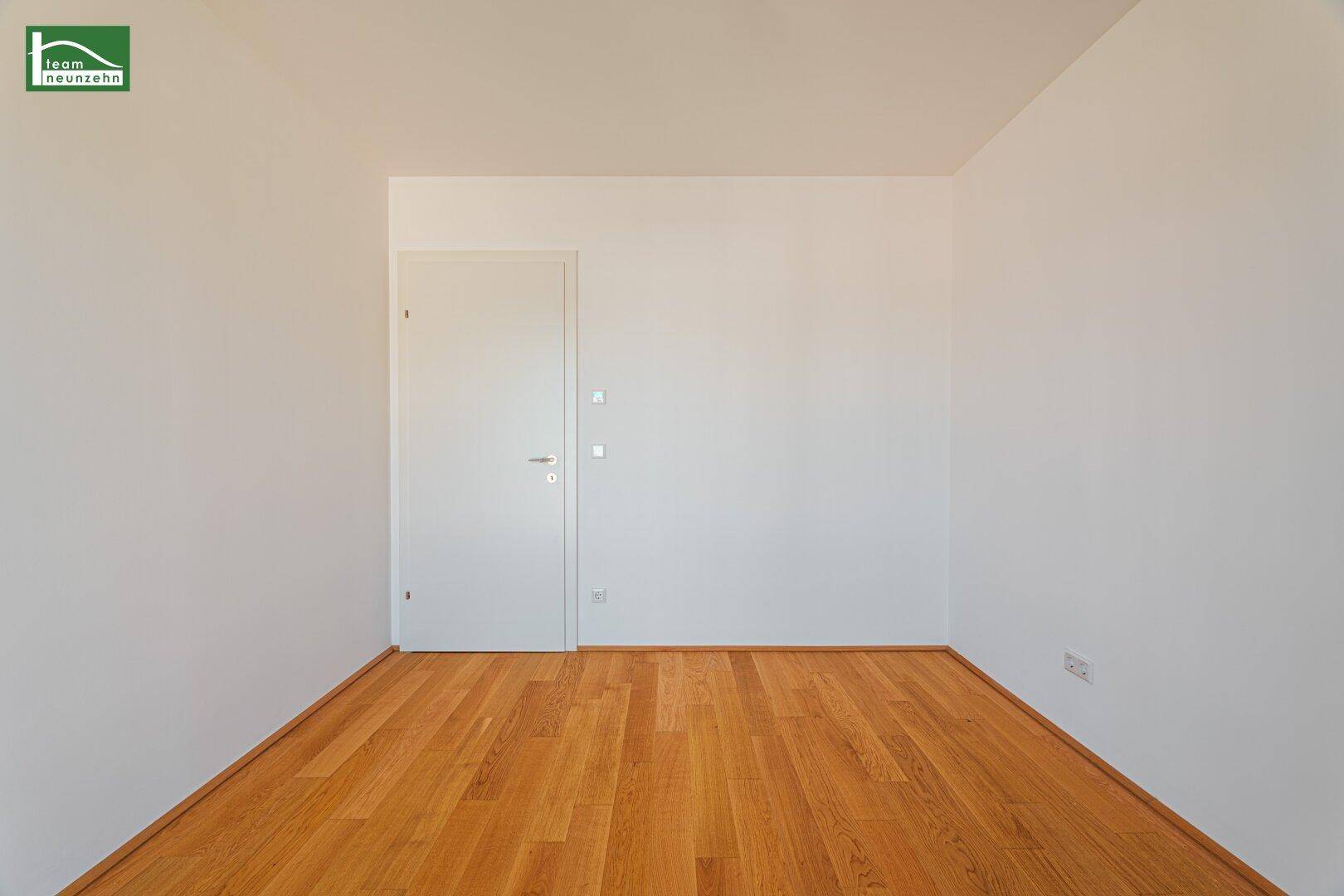 Leerer Raum mit Holzboden und einer weißen Tür, ideal für individuelle Gestaltung.
