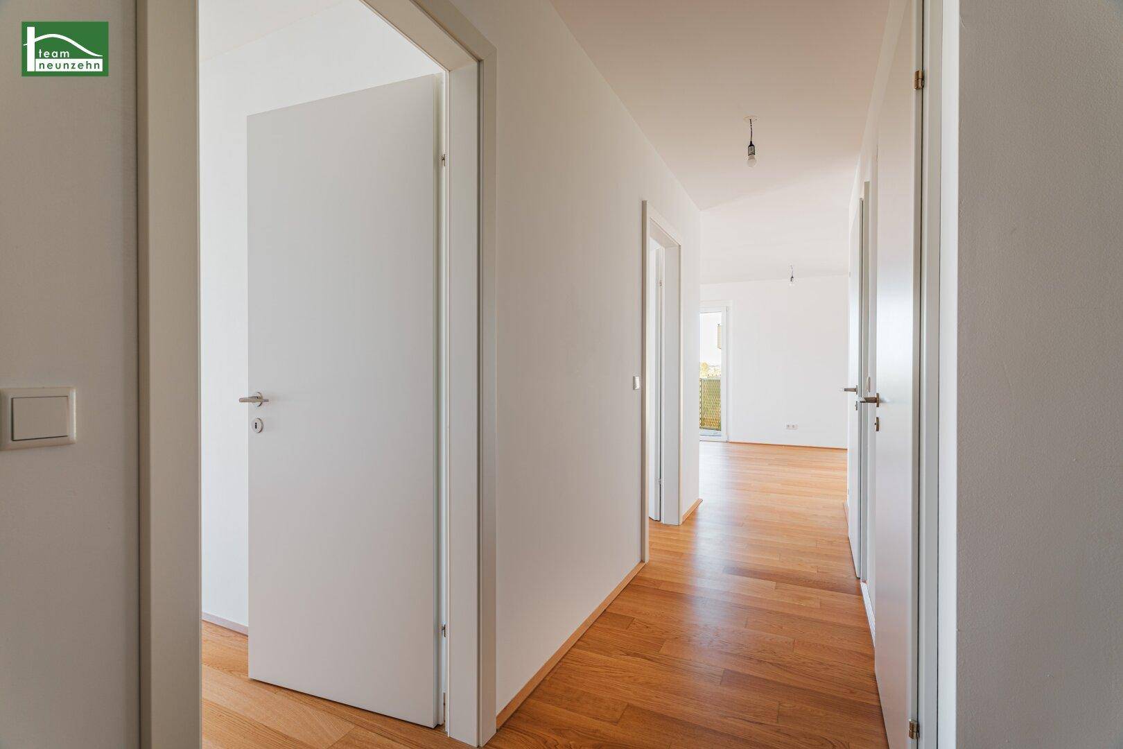 Heller Flur mit Holzboden und mehreren weißen Türen, führt zu weiteren Räumen.