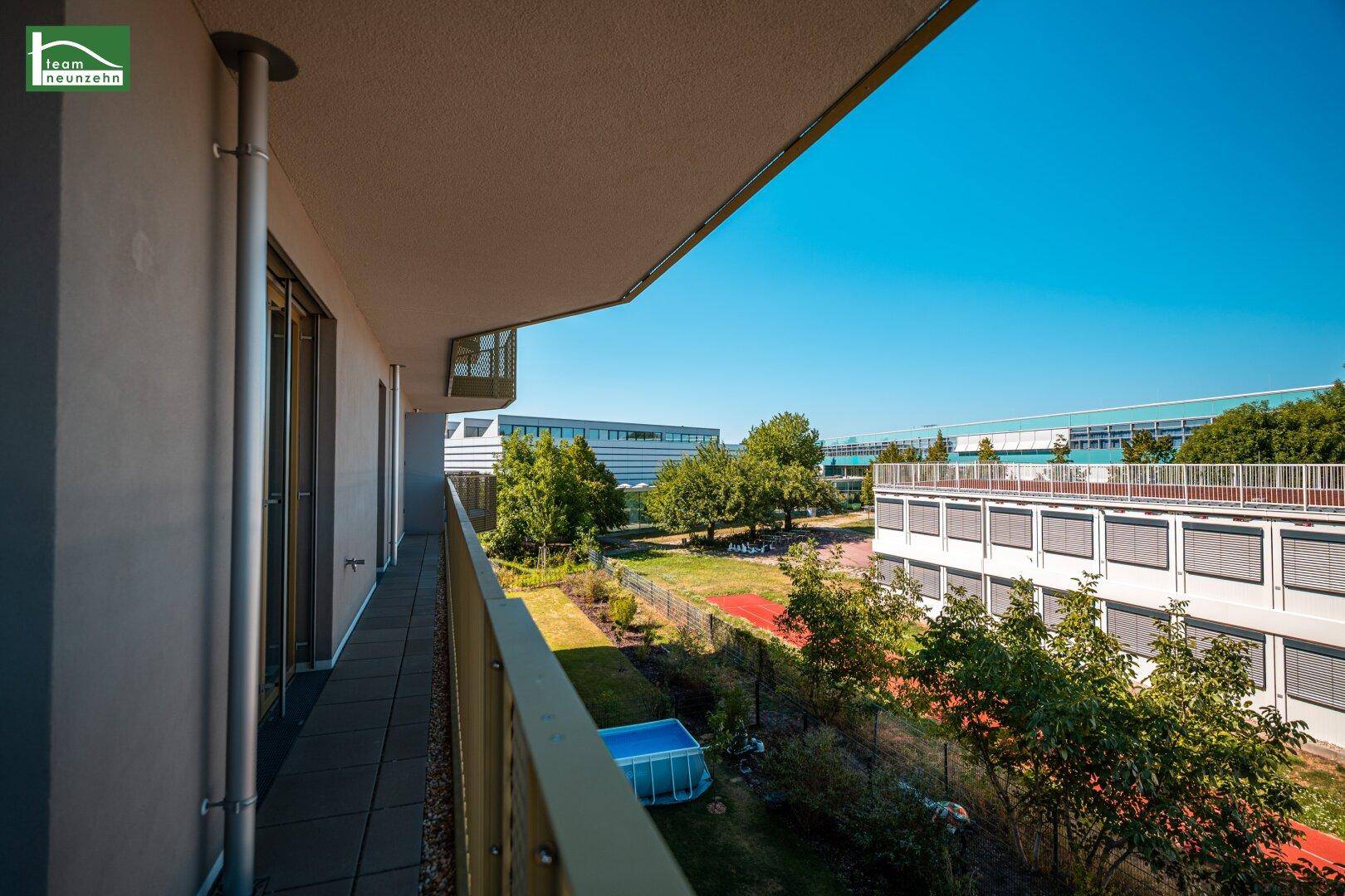 Langer Balkon mit Fliesenboden und weitem Blick auf die Umgebung und einen kleinen Pool.