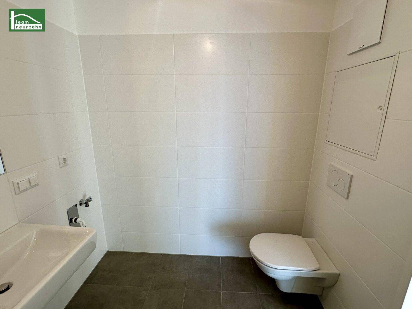 Separates WC mit wandhängender Toilette und kleinem Waschbecken.