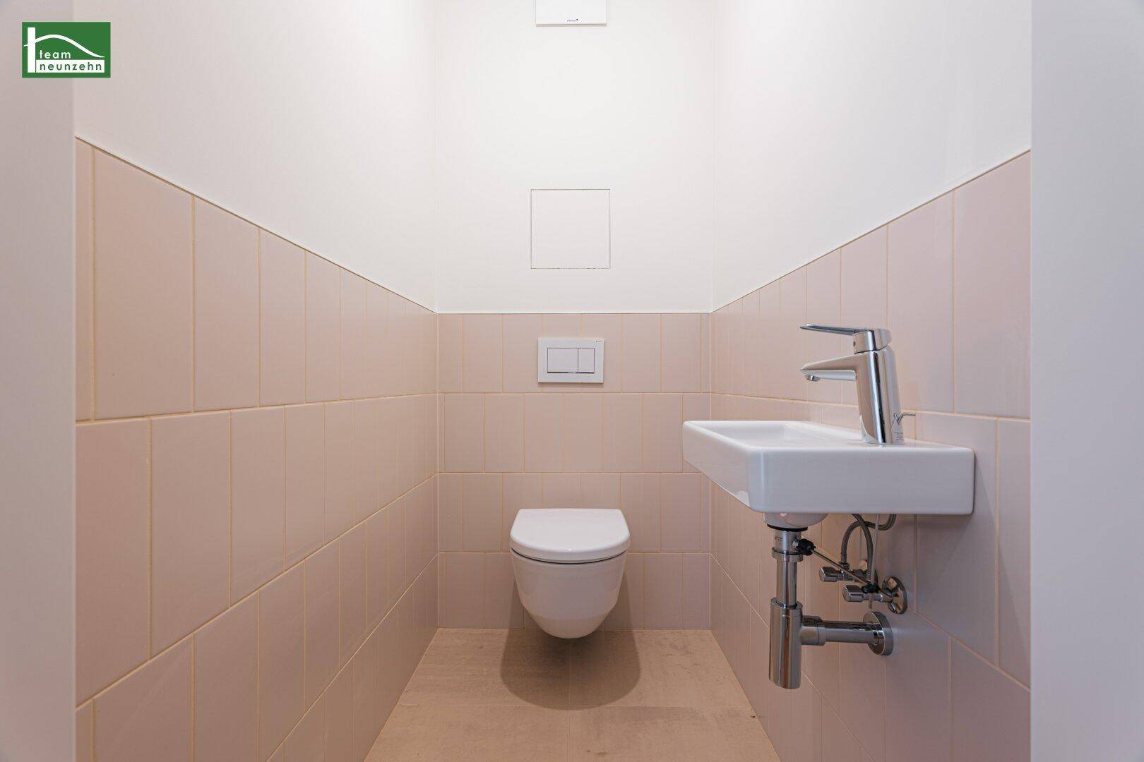 Funktionelles Gäste-WC mit wandhängender Toilette und kleinem Waschbecken in beigen Tönen.