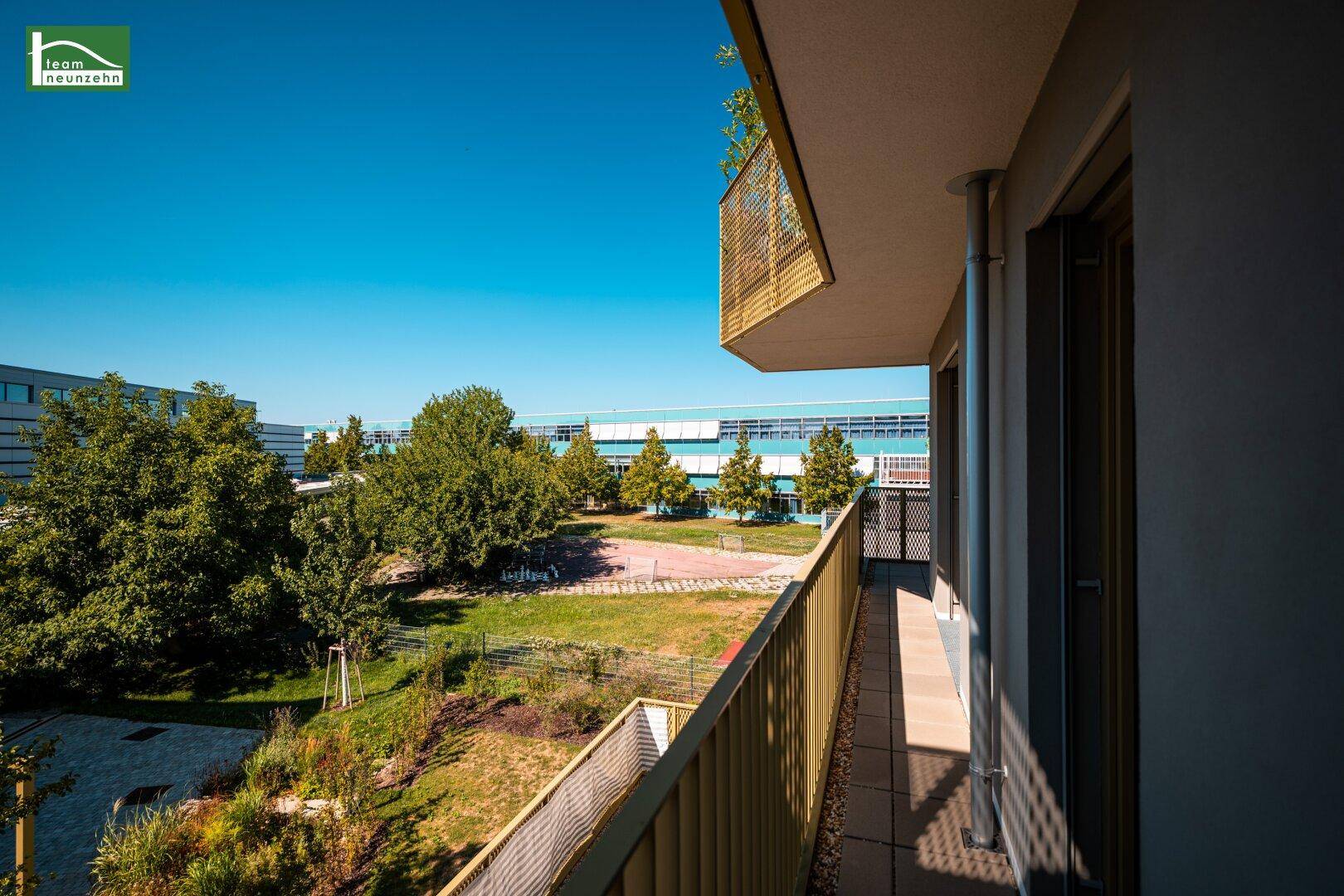Heller Balkon mit weitem Blick über grüne Bäume und die umliegende Landschaft.