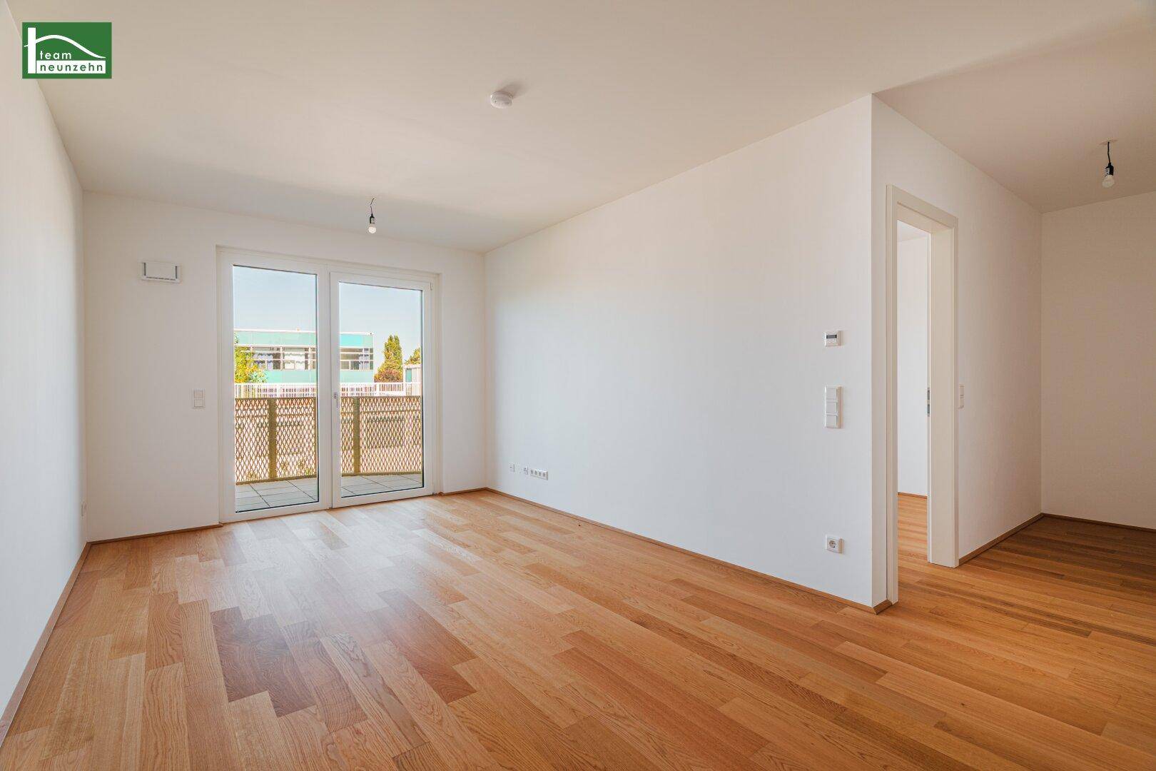 Helles, leeres Zimmer mit Holzboden und Zugang zu einem Balkon, bereit zur individuellen Gestaltung.
