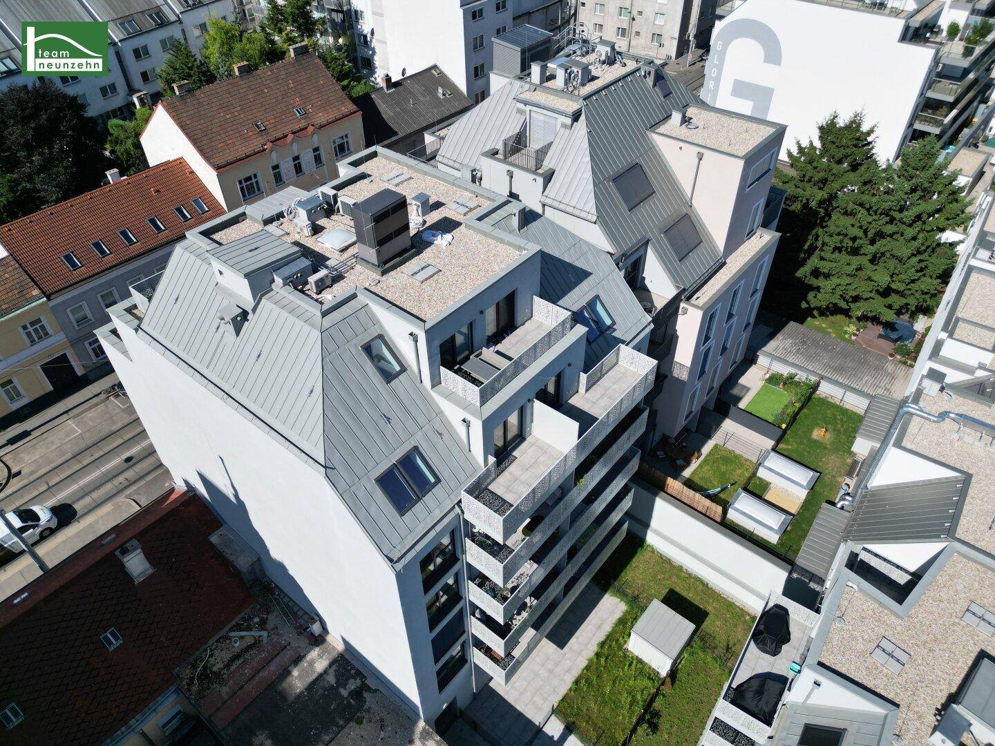 Nahaufnahme des modernen Wohnkomplexes aus der Vogelperspektive mit Balkonen und Dachflächen.