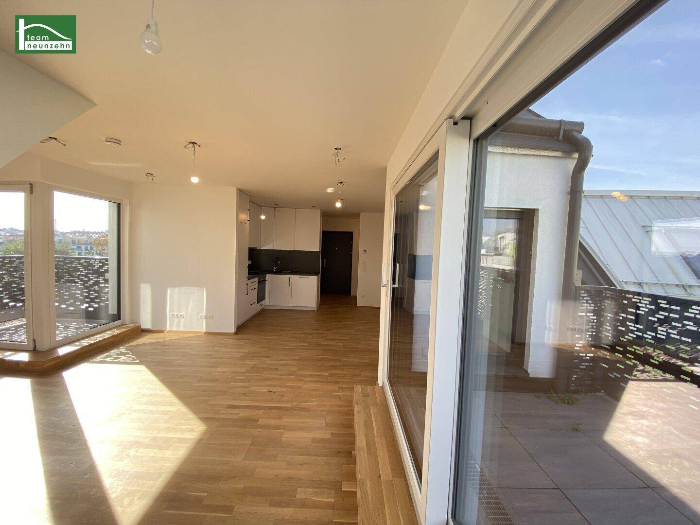 Lichtdurchfluteter offener Wohnbereich mit integrierter Küche, Parkettboden und Zugang zur Terrasse.
