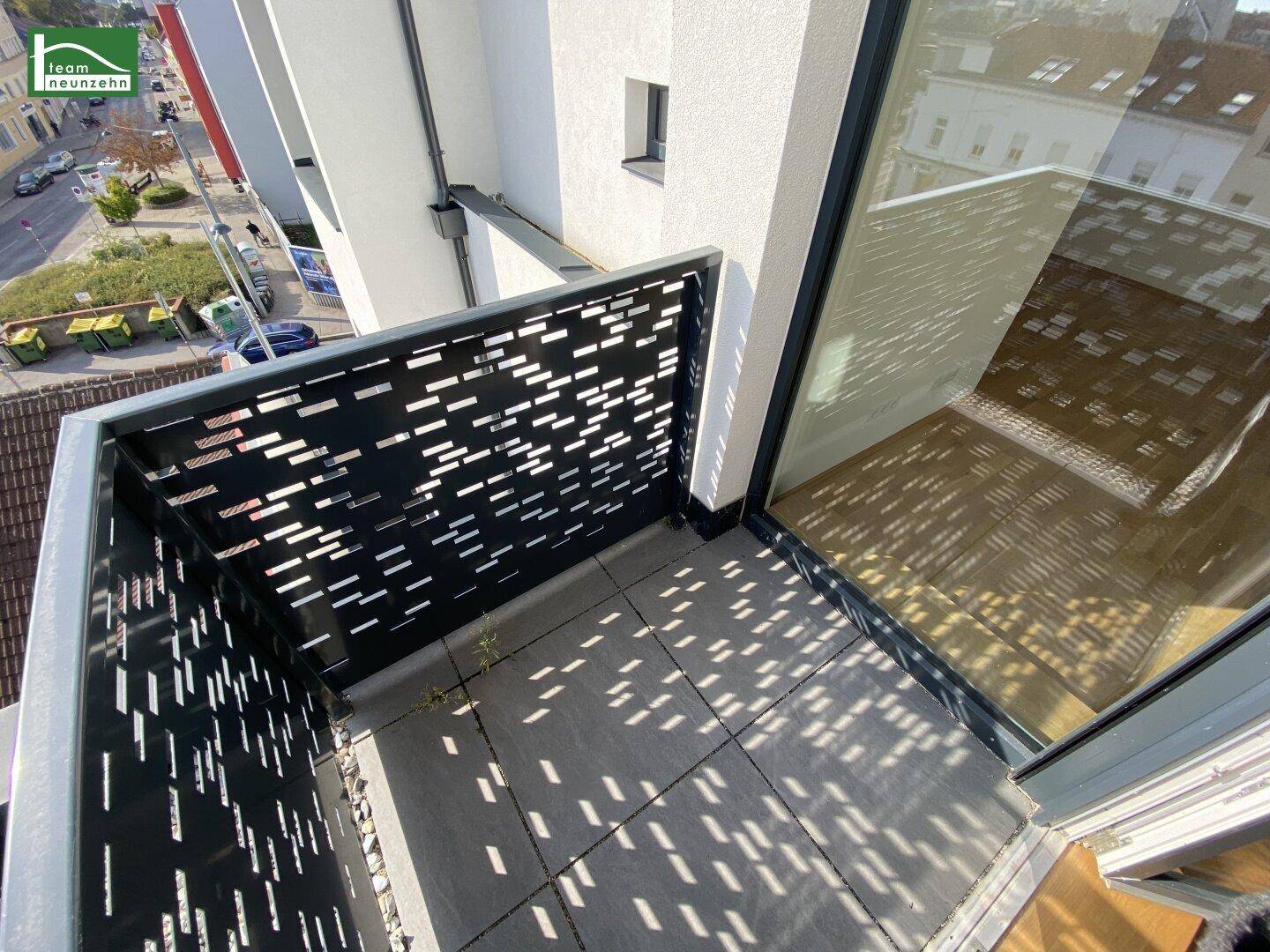 Kleiner Balkon mit Fliesenboden und modernem Lochblechgeländer, sonnendurchflutet.