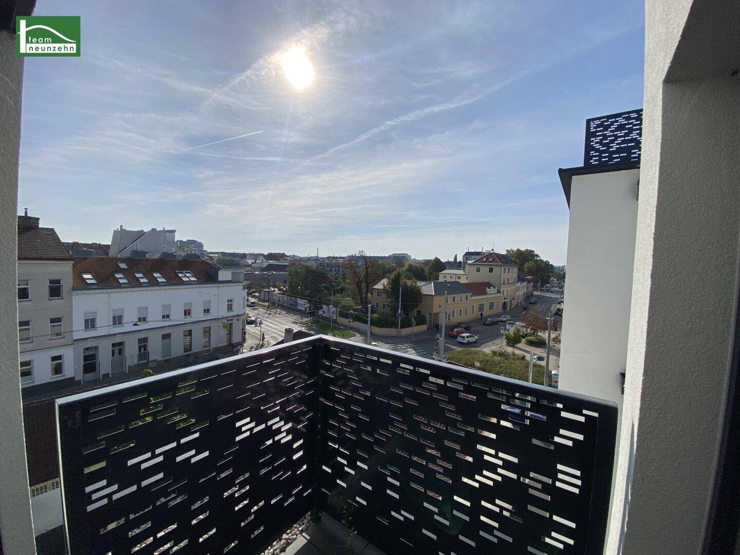 Balkon mit modernem Geländer und sonnigem Blick auf die Stadt und umliegende Gebäude.