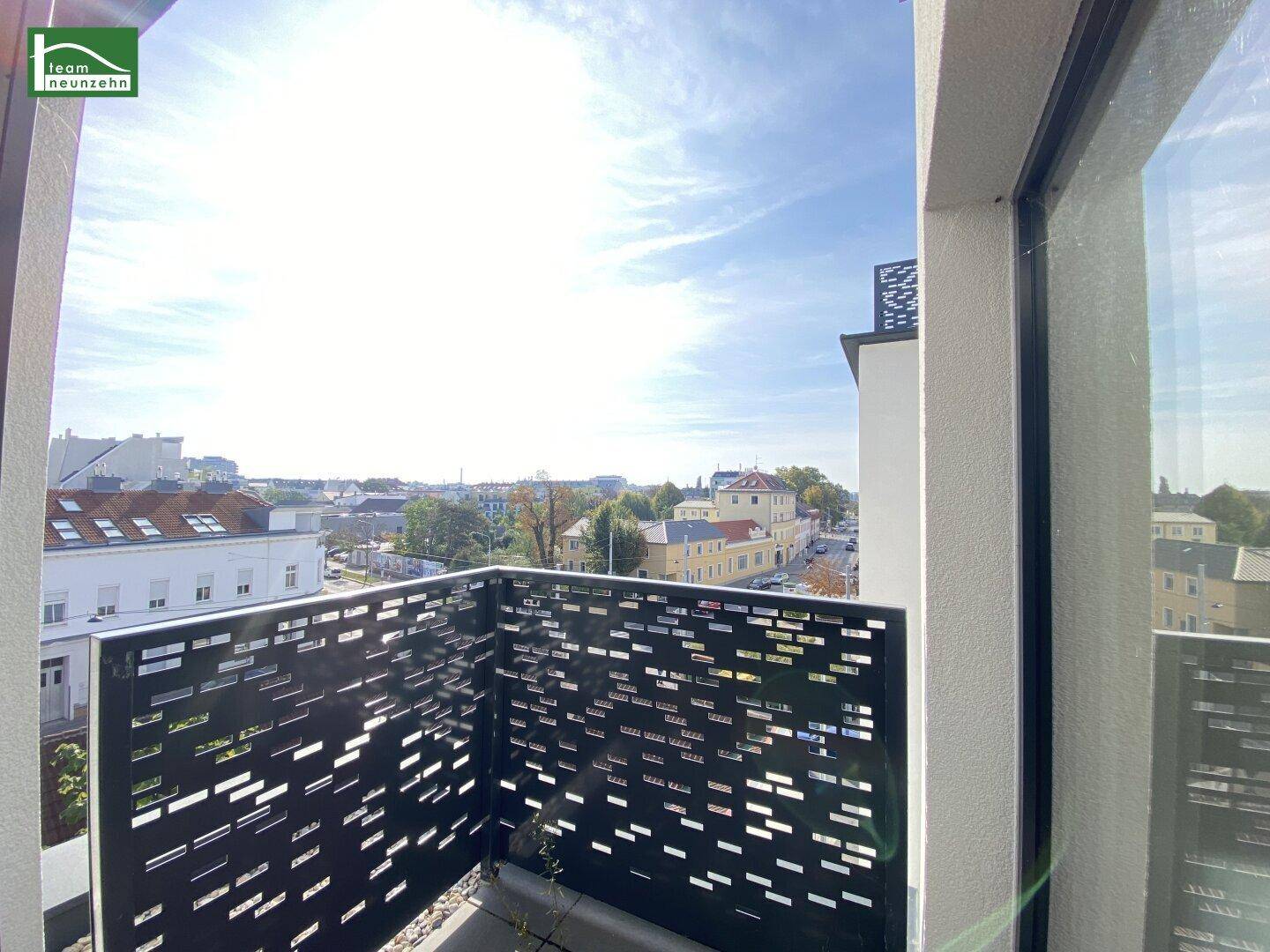 Heller Balkon mit modernem Geländer und weitem Blick über die Stadtlandschaft bei Sonnenschein.