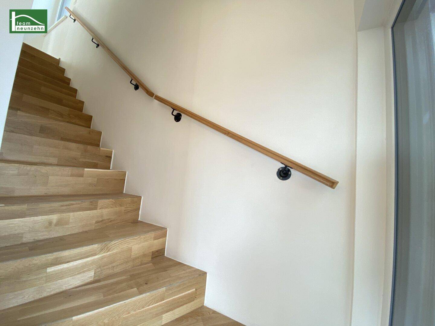 Holztreppe mit schlichtem Holzgeländer, die zu den oberen Etagen führt.