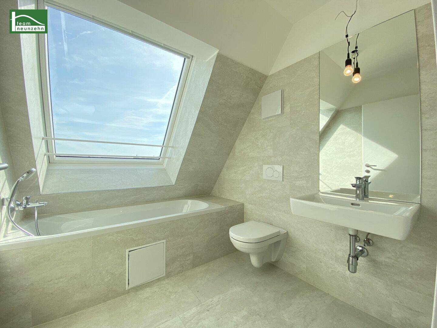 Modernes Badezimmer im Dachgeschoss mit Badewanne, Wand-WC und großem Dachfenster.
