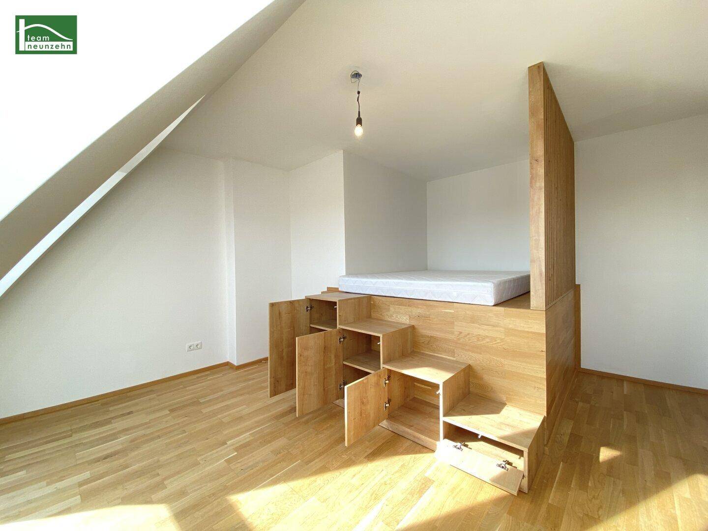 Schlafzimmer im Dachgeschoss mit integriertem Bettpodest und Stauraum, hell und funktional.