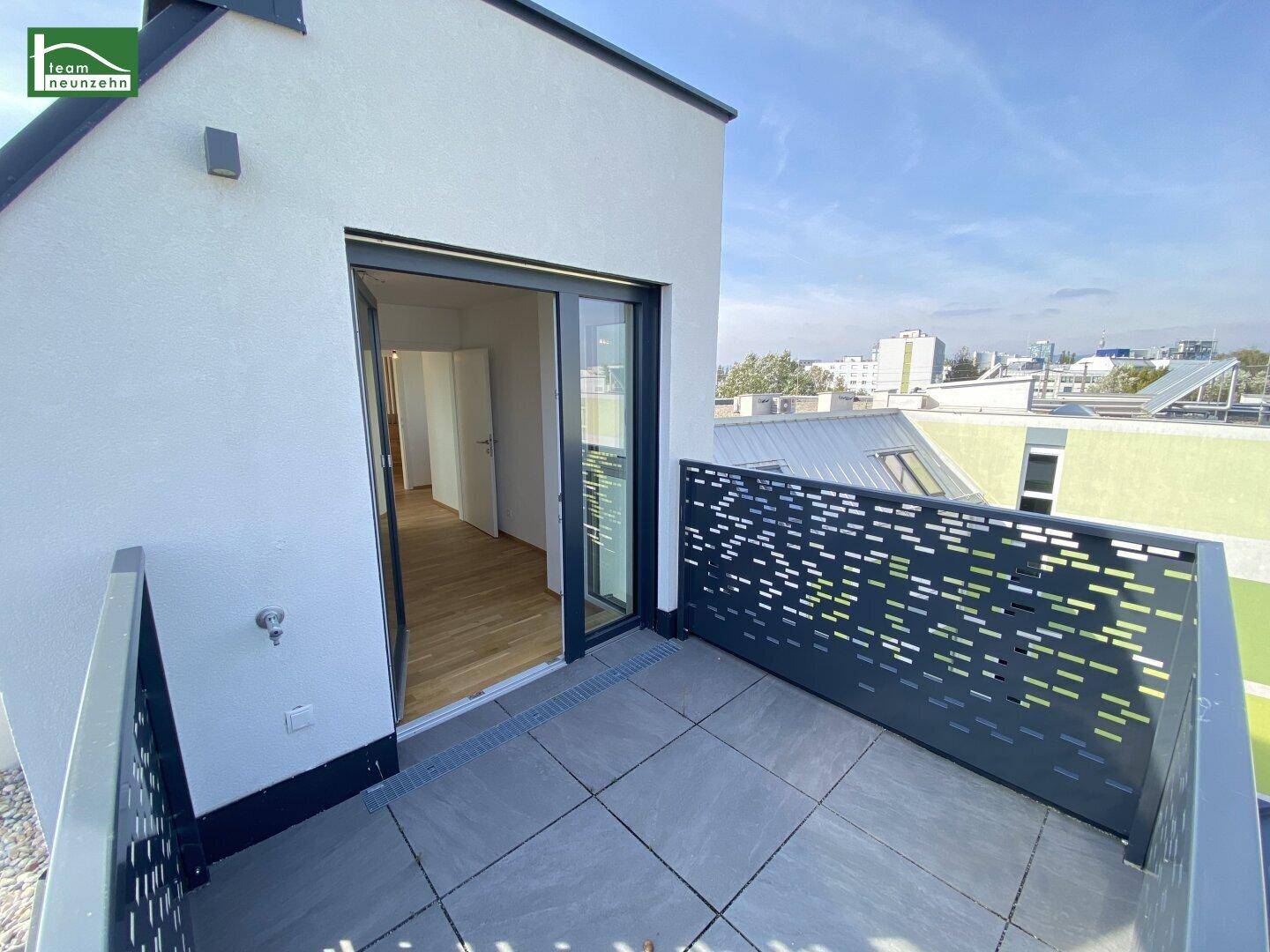 Kleiner Balkon mit Fliesenboden und Zugang zu einem hellen Innenraum mit Holzparkett.