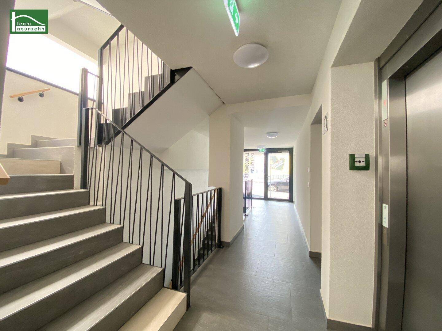Heller Flur im Treppenhaus mit Zugang zum Aufzug und Ausgang ins Freie.