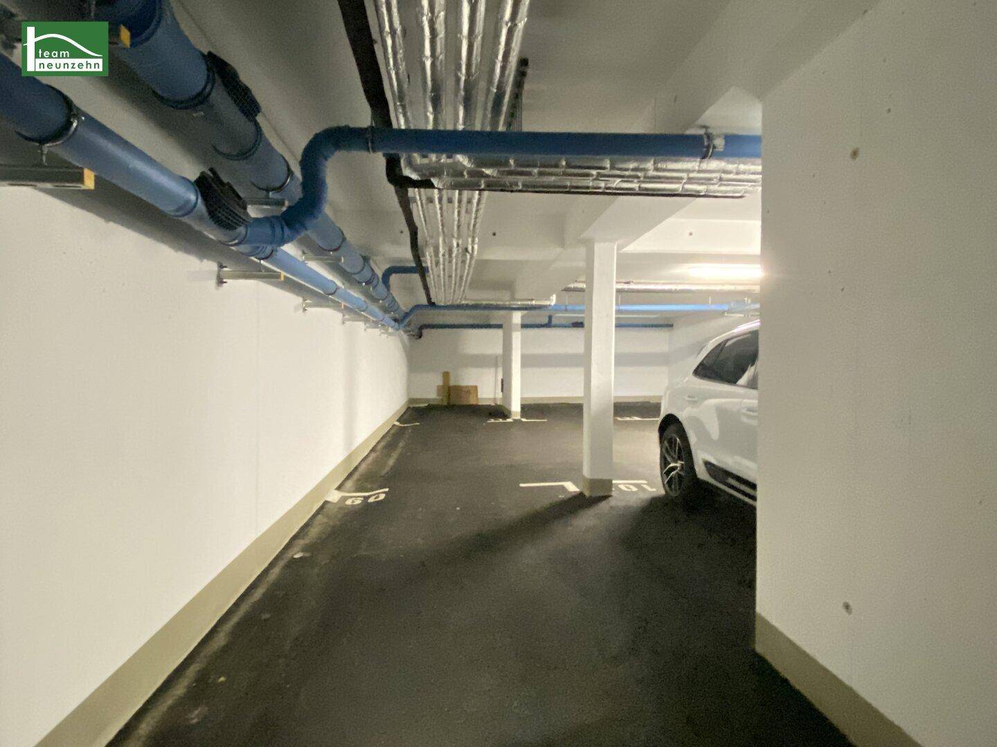 Tiefgarage mit sichtbaren Leitungen an der Decke und einem geparkten Fahrzeug.