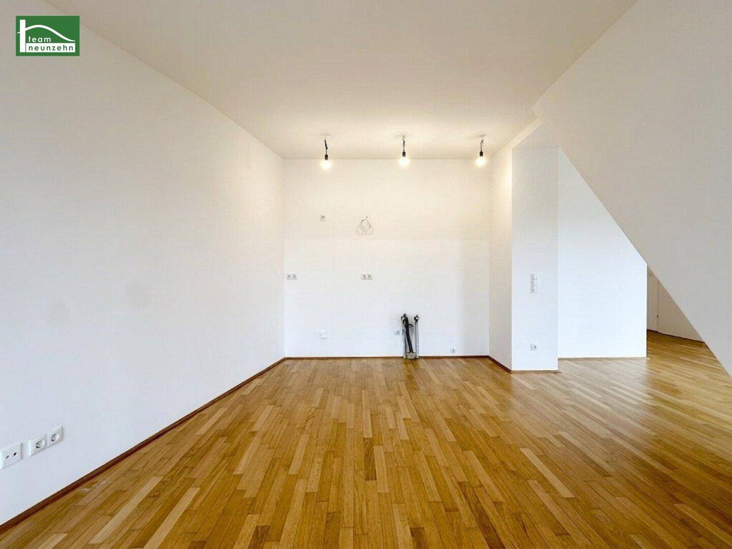 Geräumiges Zimmer mit Holzboden, weißen Wänden und Dachschräge.
