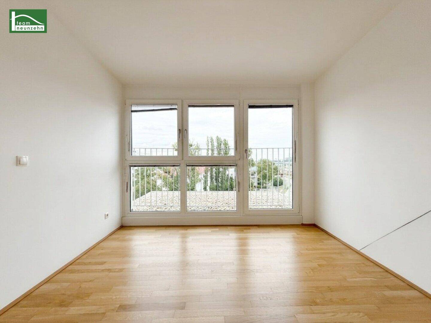 Lichtdurchfluteter Raum mit großen Fenstern und Blick ins Grüne, ideal für Wohn- oder Schlafzimmer.