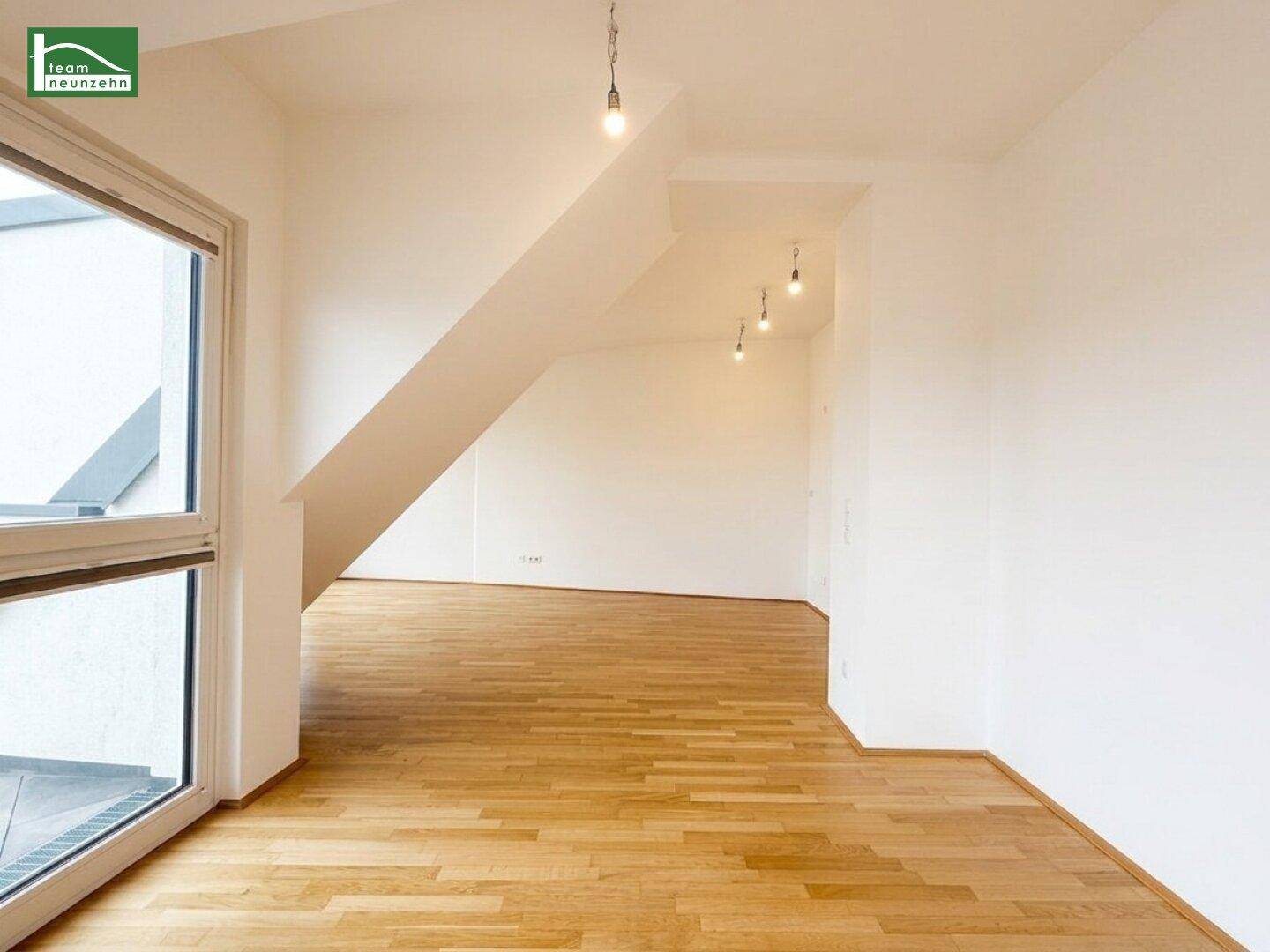 Heller Raum mit Holzboden und großem Fenster, bietet viel Tageslicht und flexible Nutzungsmöglichkeiten.