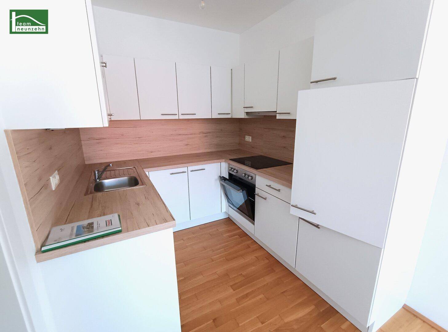 Moderne Einbauküche mit weißen Schränken, Holzoptik-Arbeitsplatte und integrierten Geräten.