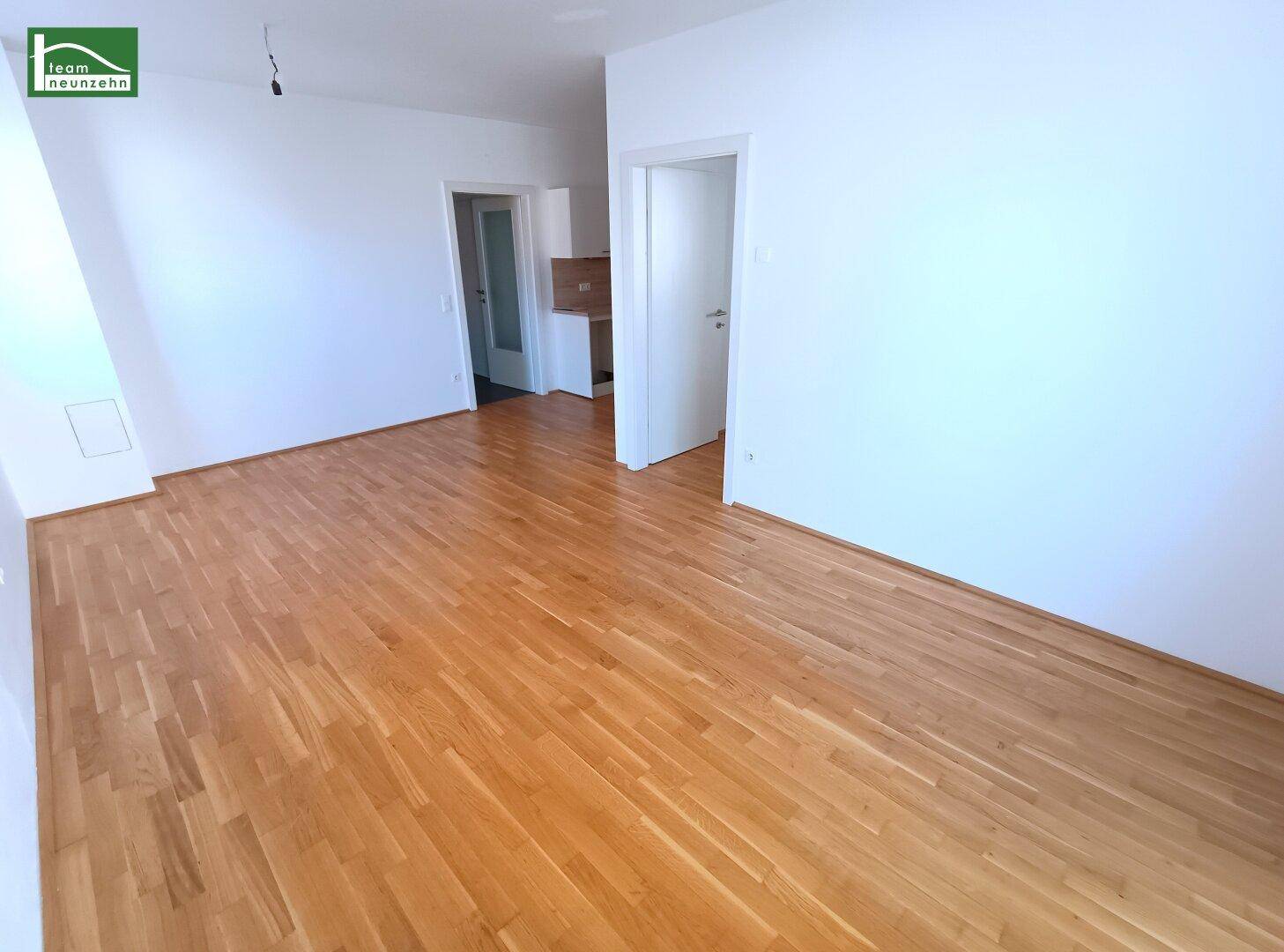 Leeres Wohnzimmer mit Parkettboden und weißen Wänden, bereit zur individuellen Gestaltung.