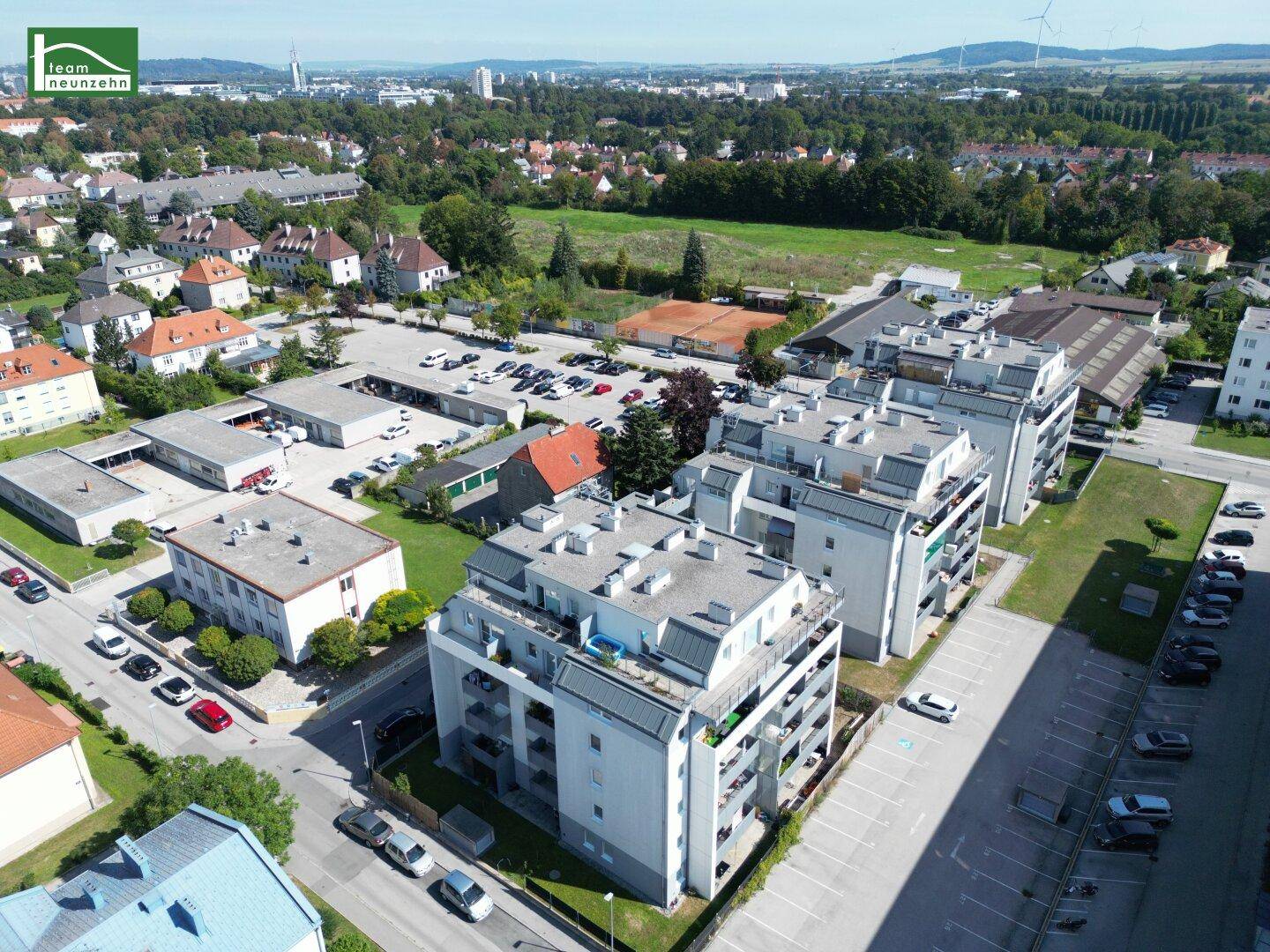 Luftaufnahme des modernen Wohnkomplexes mit umliegenden Gebäuden und Grünflächen.