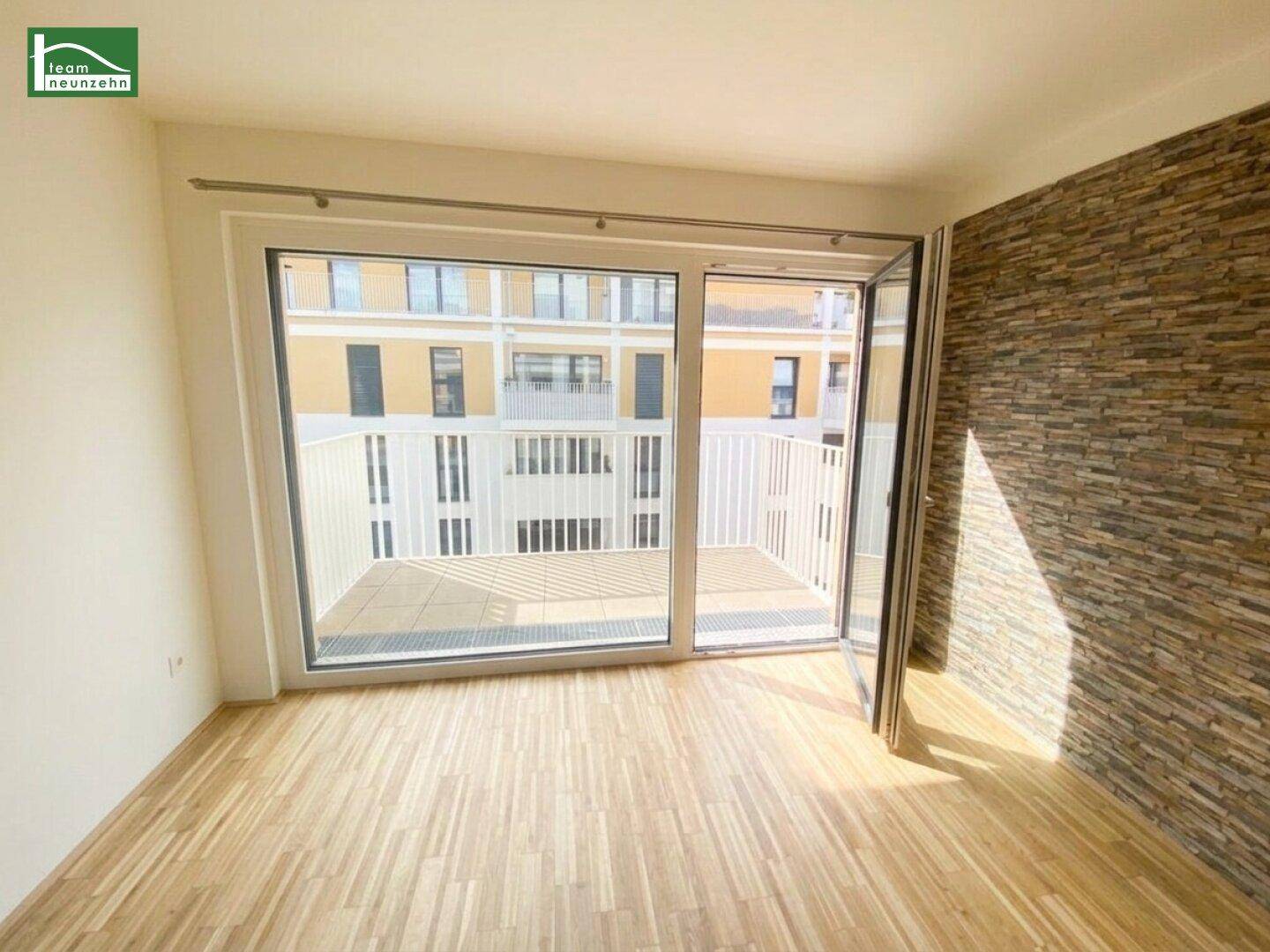 Lichtdurchflutetes Wohnzimmer mit Zugang zum Balkon und dekorativer Wandverkleidung.
