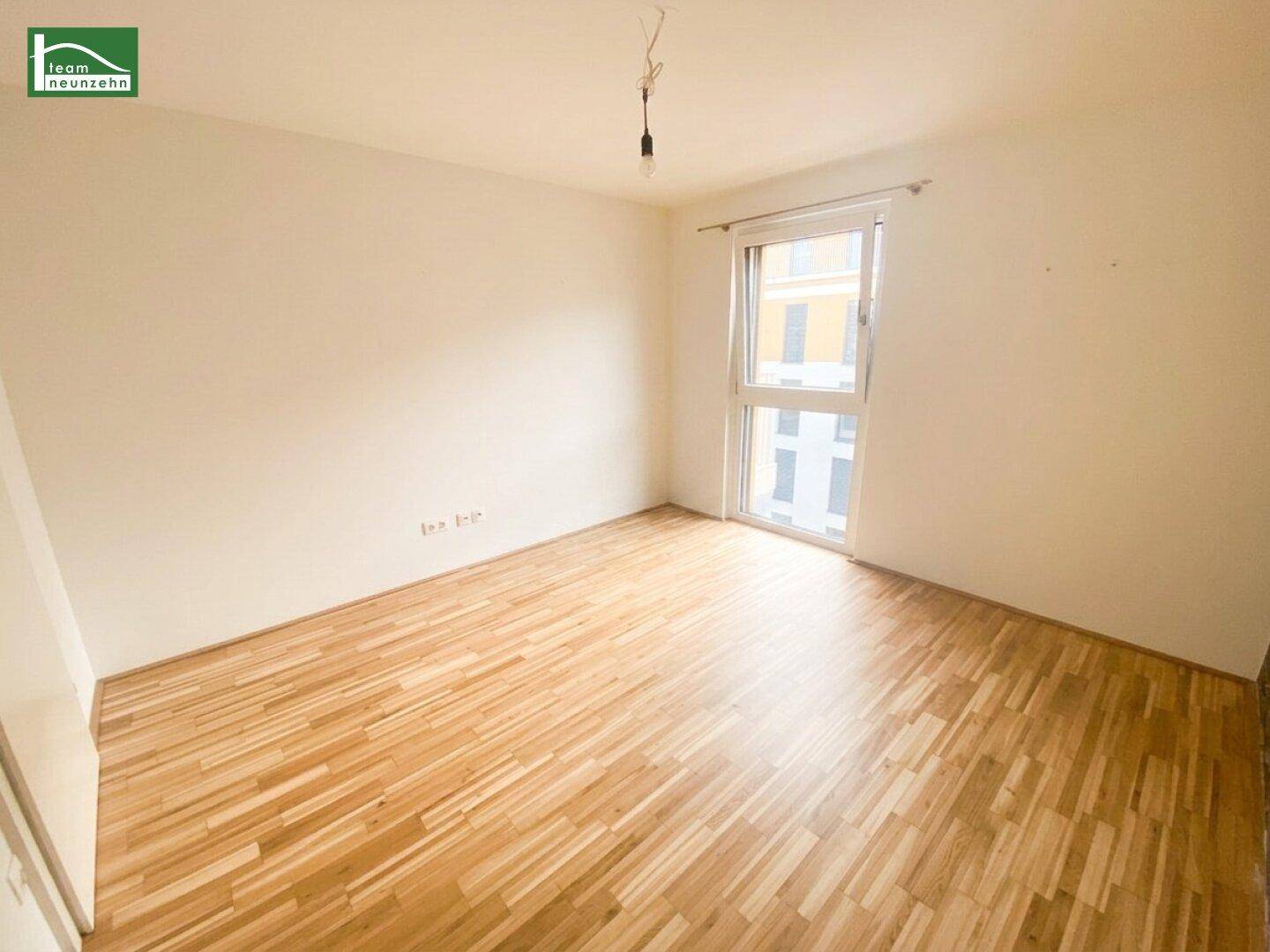 Helles Schlafzimmer mit Parkettboden und einem Fenster, bereit zur individuellen Gestaltung.