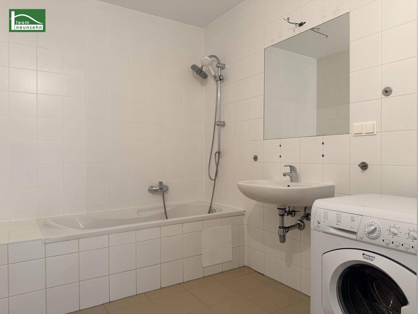 Funktionales Badezimmer mit Badewanne, Dusche, Waschbecken und Waschmaschine.