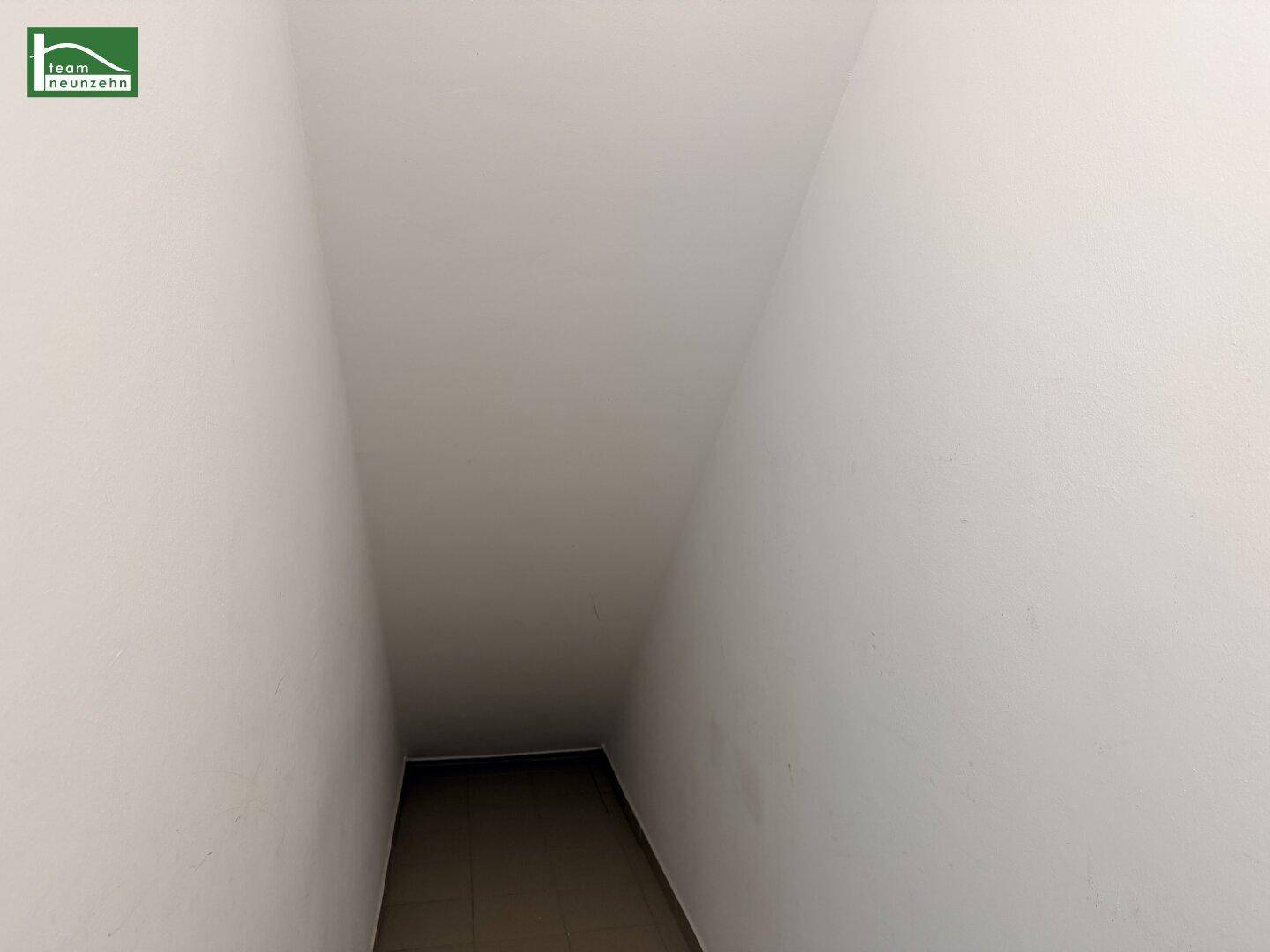 Schmaler Gang oder Treppenaufgang mit einfacher Gestaltung und begrenztem Licht.