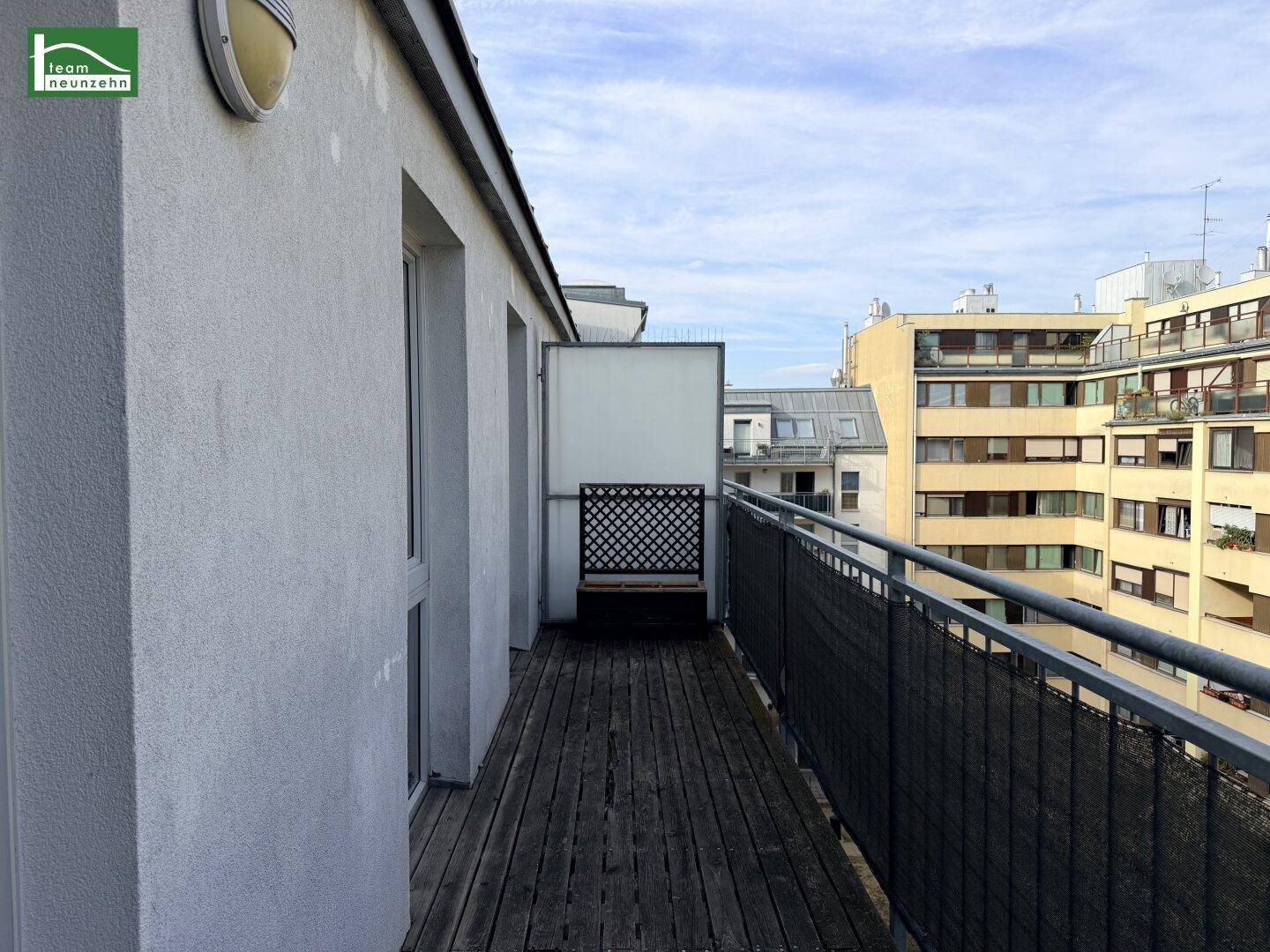 Geräumiger Balkon mit Holzdielen und weitem Blick über die Stadt.
