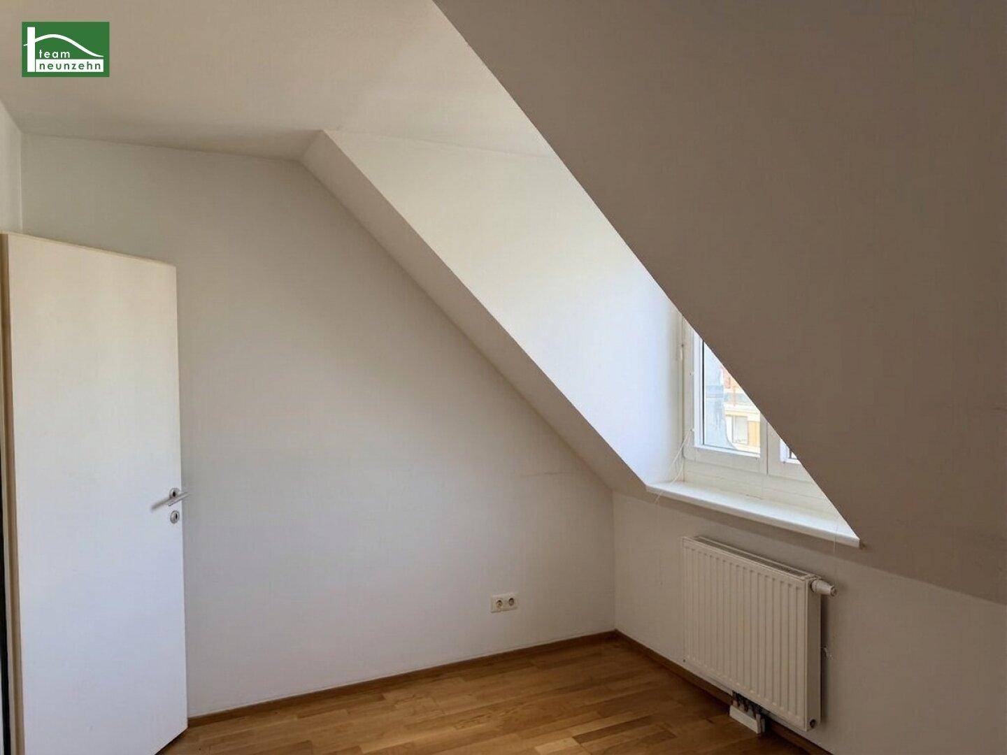 Gemütliches Zimmer im Dachgeschoss mit schräger Decke und einem Fenster für Tageslicht.