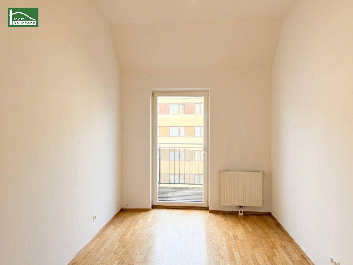Lichtdurchflutetes Zimmer mit Parkettboden und Zugang zu einem französischen Balkon.