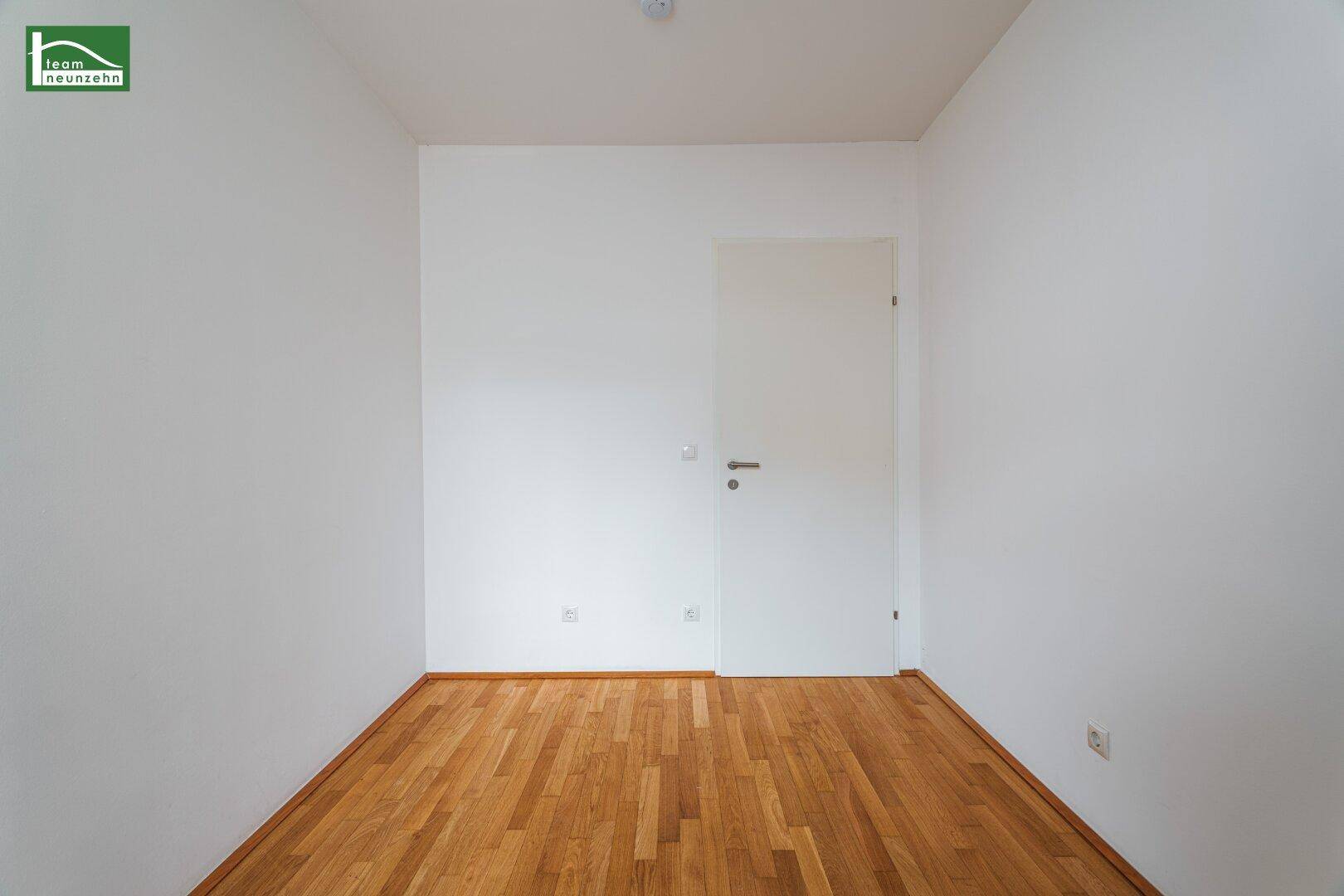Leeres Zimmer mit Parkettboden und weiß gestrichenen Wänden, bereit zur individuellen Gestaltung.