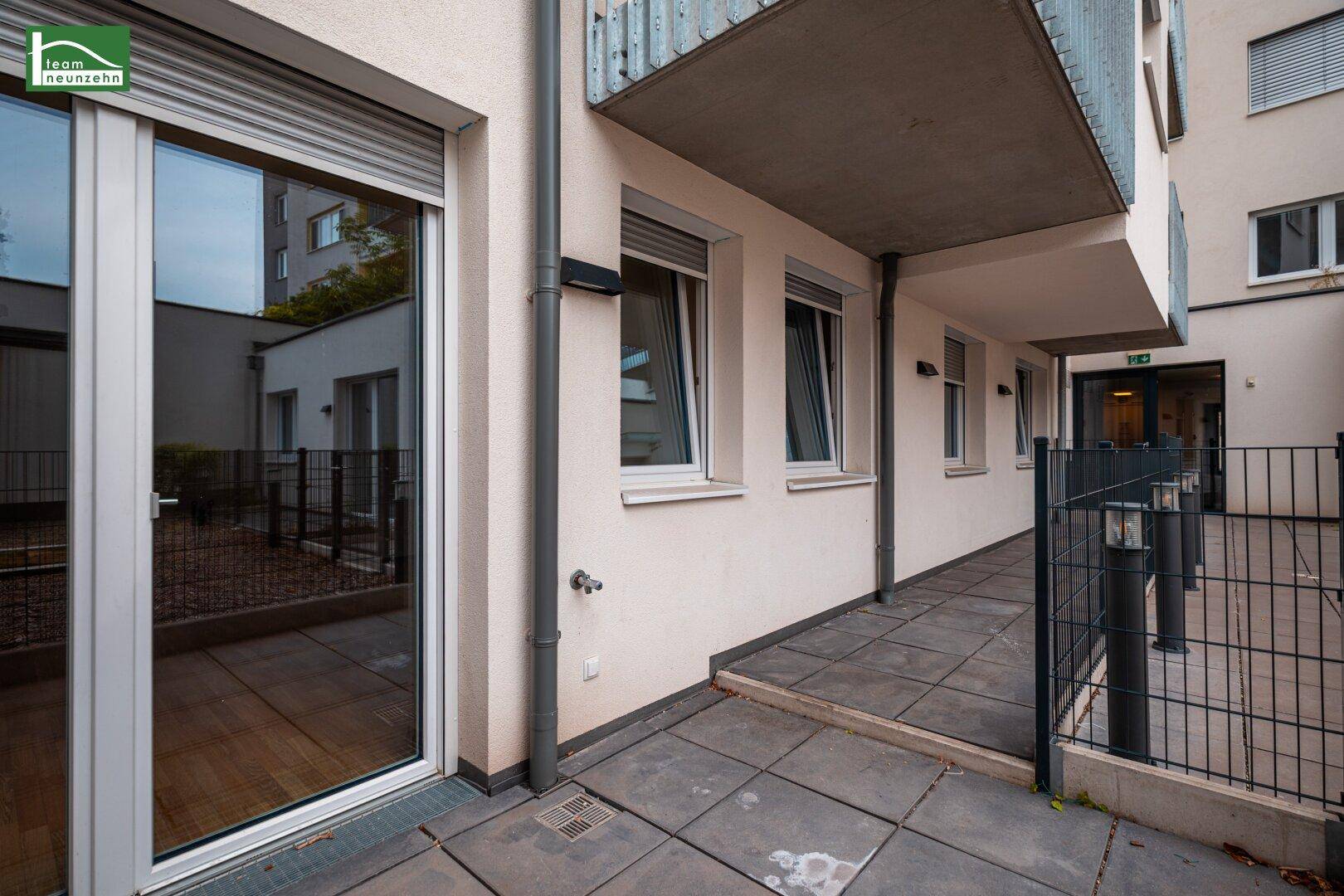 Außenbereich mit gepflastertem Weg und Zugang zu einer Terrasse, umgeben von moderner Architektur.