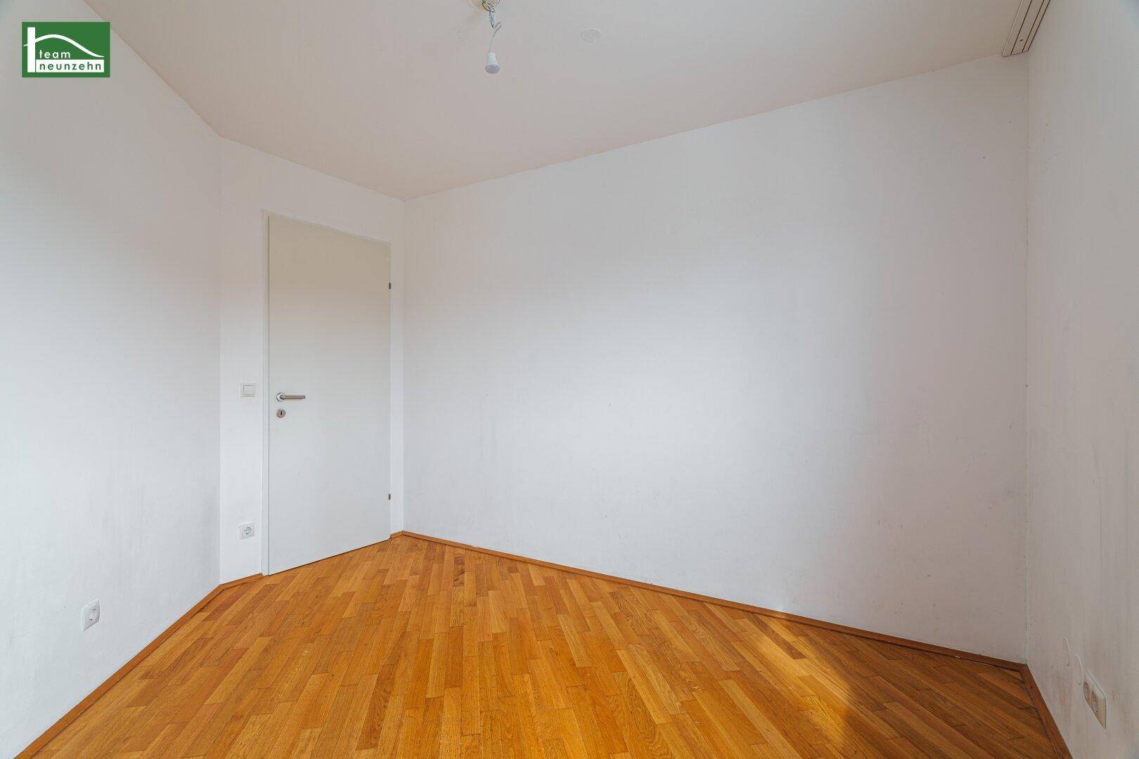 Leeres Zimmer mit hellem Parkettboden und weiß gestrichenen Wänden, bereit zur Einrichtung.