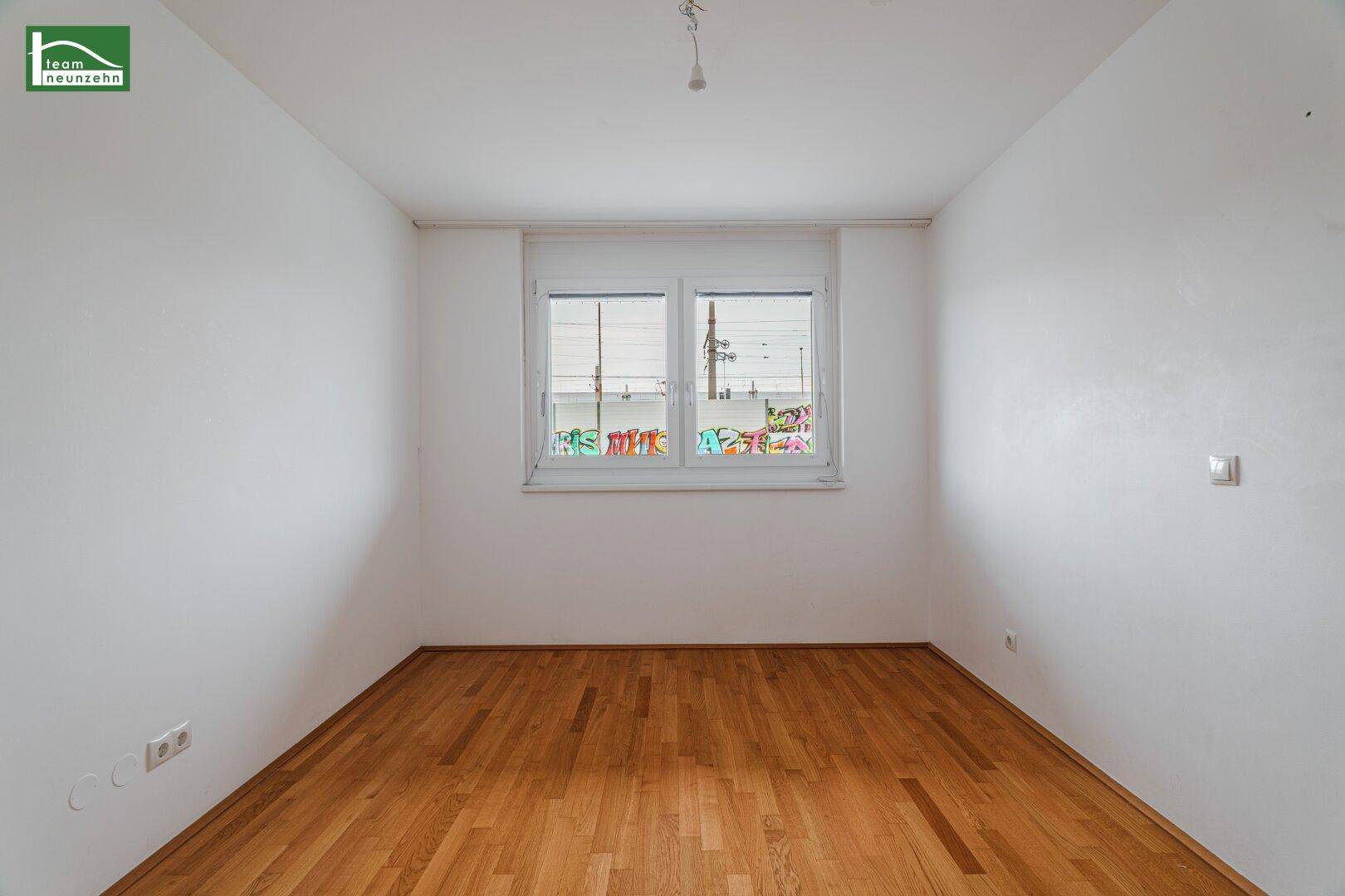 Helles, leeres Zimmer mit Parkettboden und einem Fenster, bietet viel Potenzial für individuelle Gestaltung.