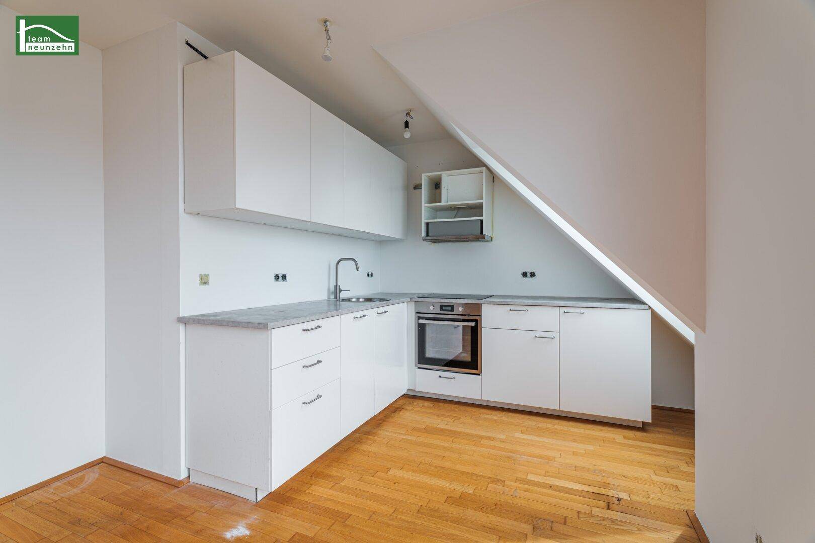 Moderne Küchenzeile mit weißen Schränken, integriertem Backofen und Arbeitsplatte.