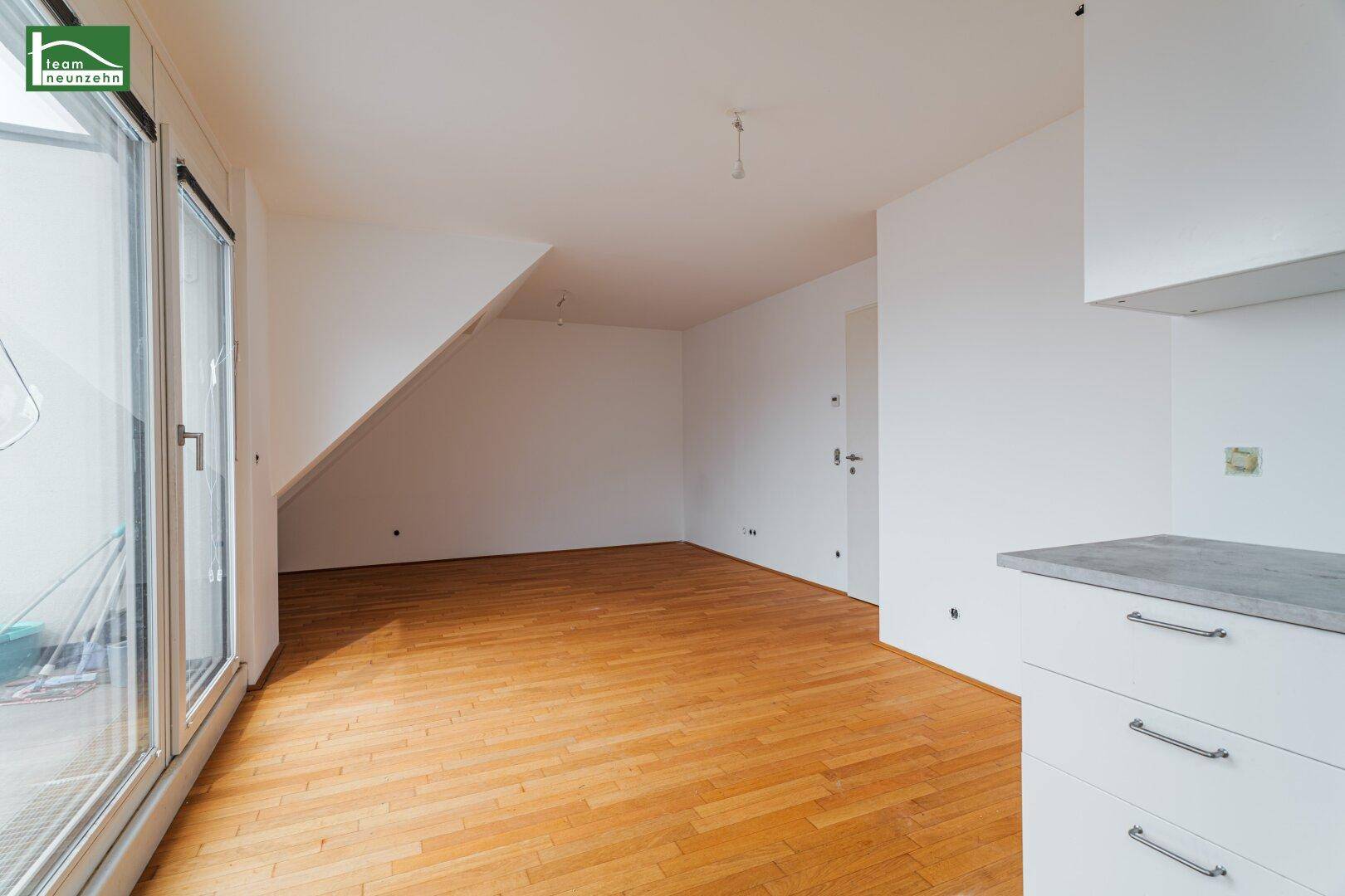 Heller Wohnbereich mit Holzboden und großen Fenstern, die Zugang zum Balkon bieten.