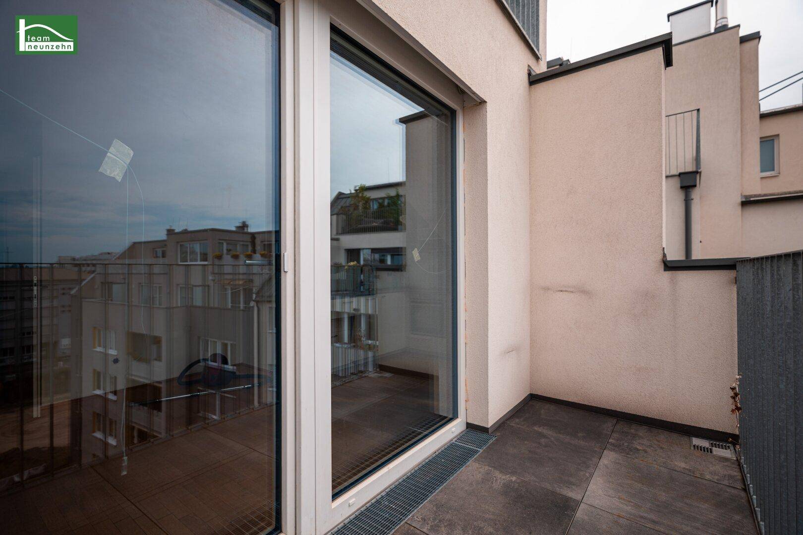 Geräumiger Balkon mit Fliesenboden und Blick auf die umliegenden Gebäude der Stadt.