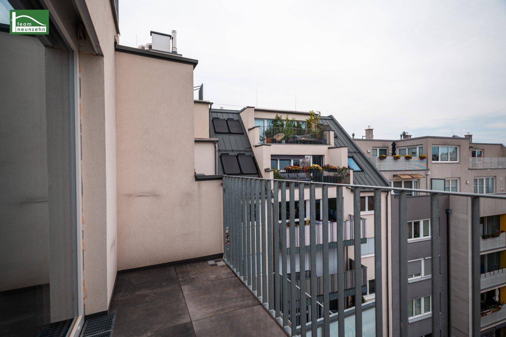 Balkon mit moderner Metallbrüstung und weitem Blick über die Dächer der Stadt und andere Gebäude.