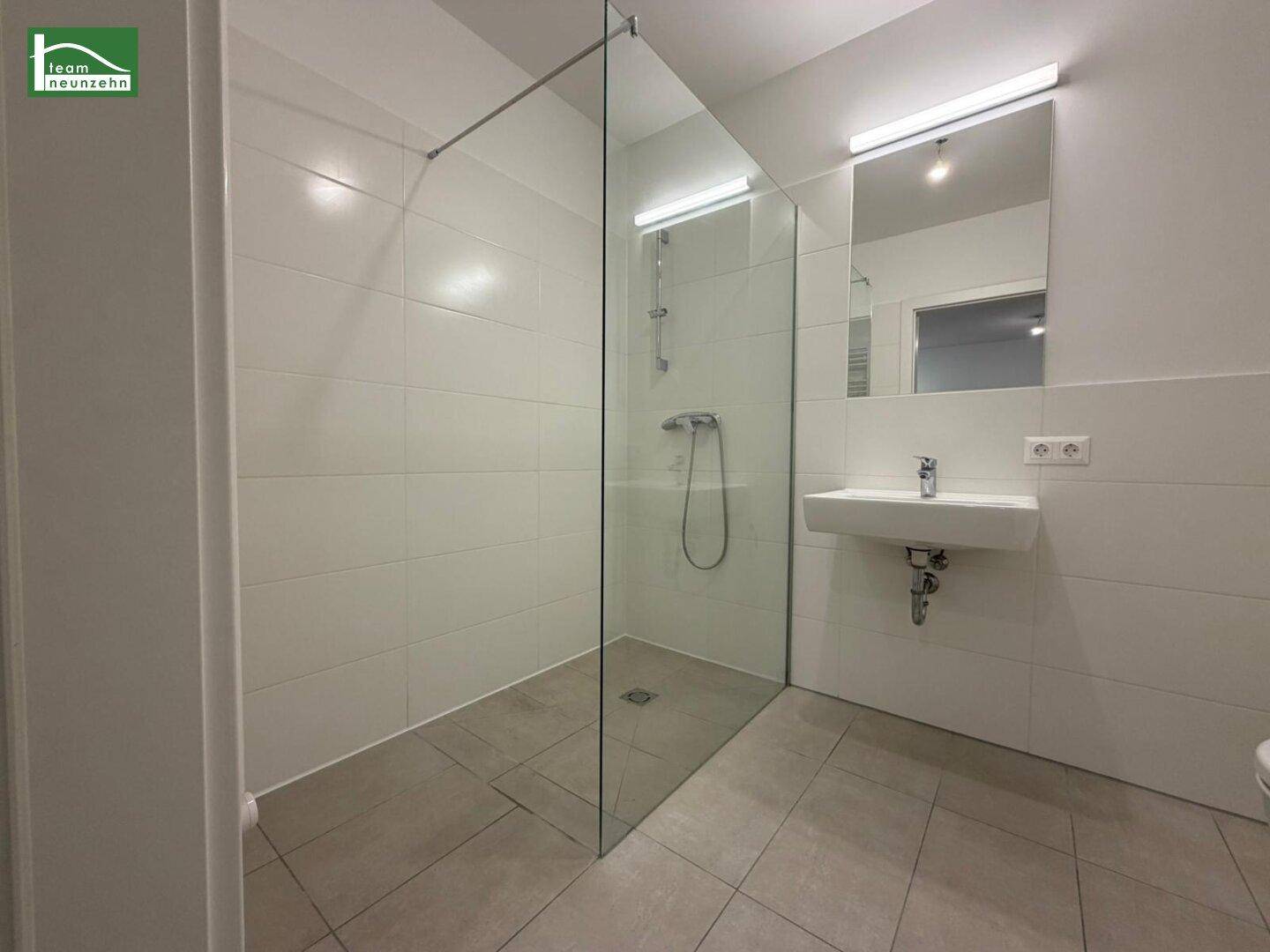 Modernes Badezimmer mit ebenerdiger Dusche und eleganten Fliesen, bietet Komfort und Funktionalität.