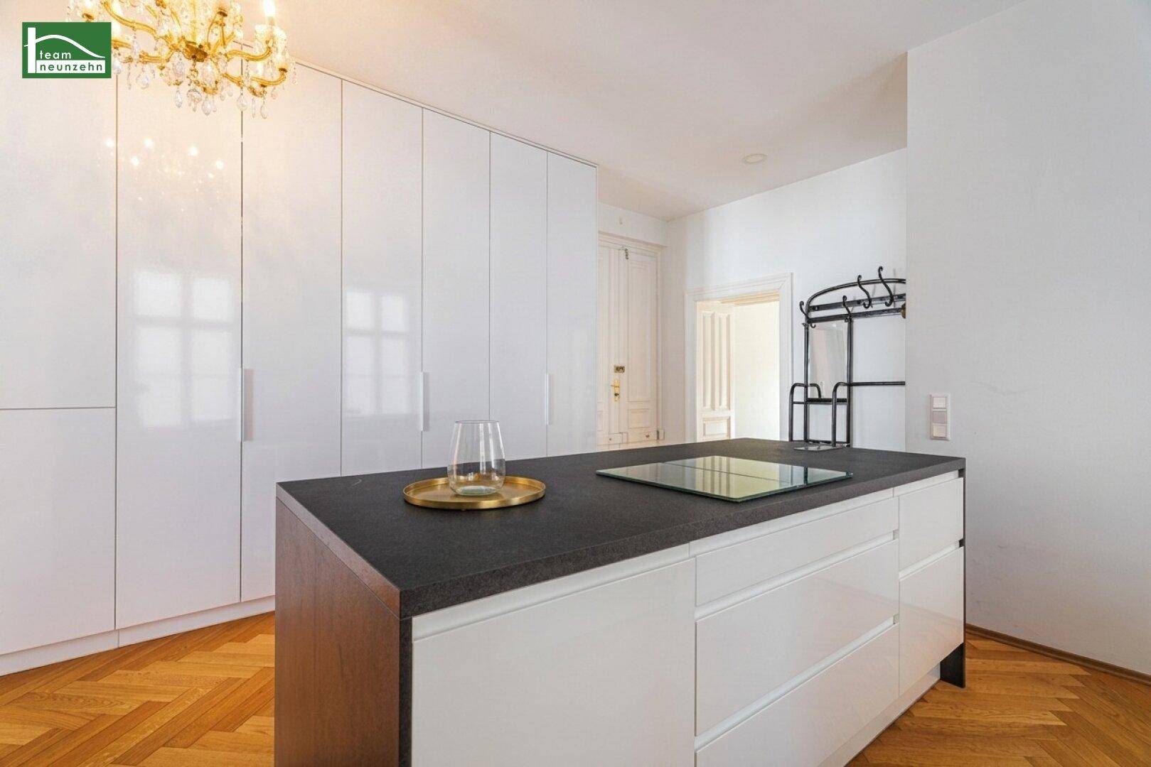 Elegante weiße Hochglanzküche mit integrierten Geräten und Kochfeld auf der Kücheninsel.