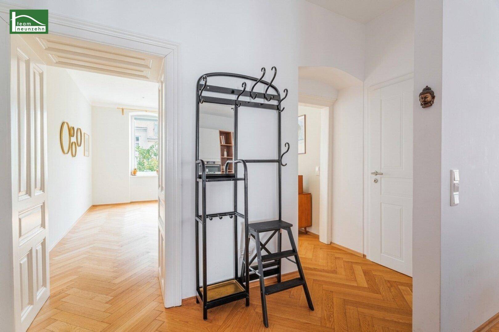 Heller Eingangsbereich mit Garderobe und Zugang zu weiteren Zimmern mit Fischgrätparkett.