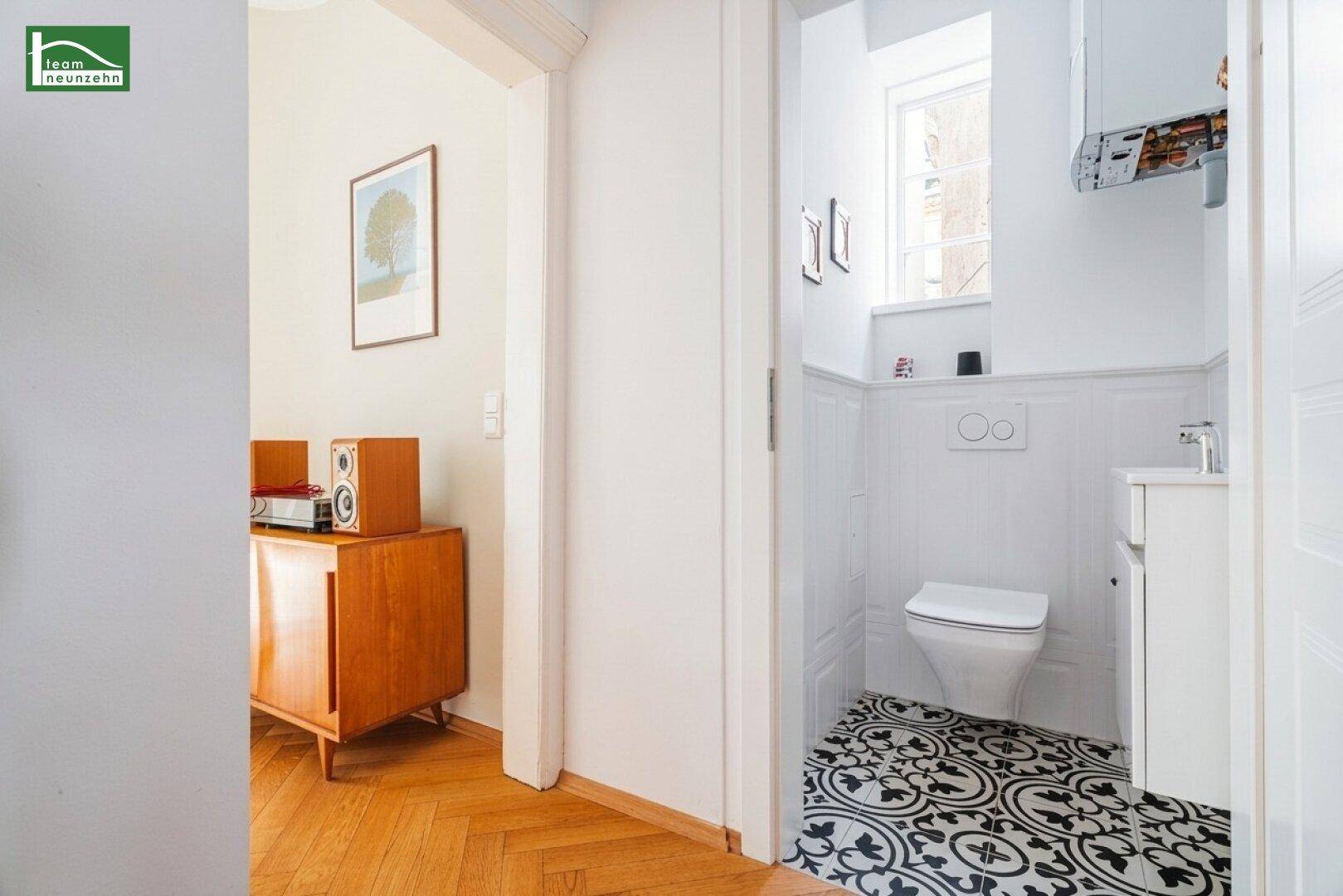 Modernes Gäste-WC mit gemusterten Fliesen, wandhängendem WC und kleinem Fenster.