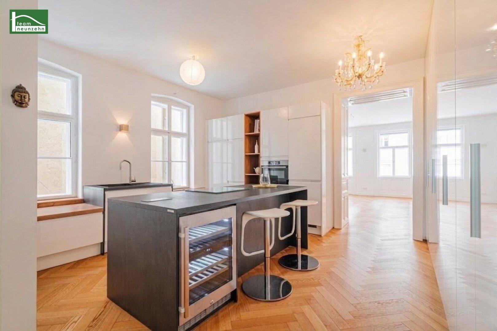 Moderne Küche mit Kücheninsel, Weinkühler und Blick in den angrenzenden Wohnbereich.