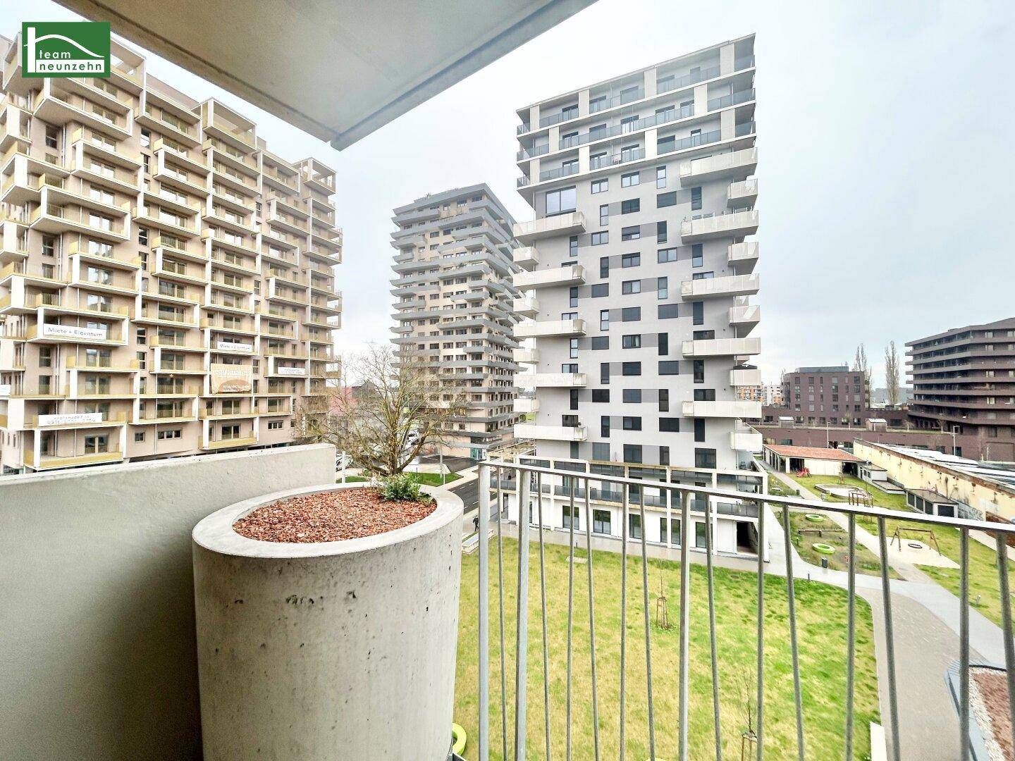 Balkon mit Blick auf moderne Wohngebäude und eine gepflegte Grünfläche in der Umgebung.