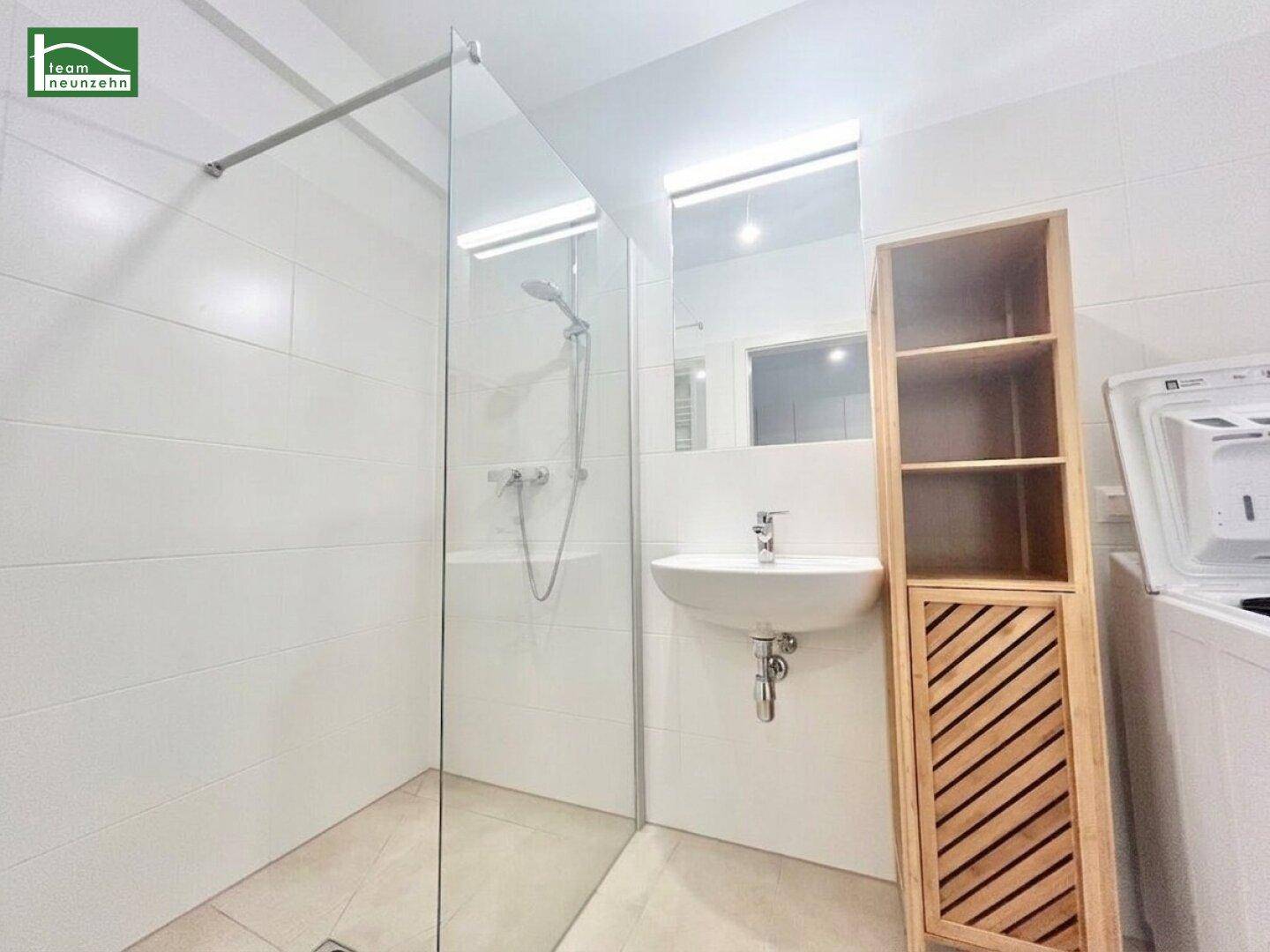 Modernes Badezimmer mit ebenerdiger Dusche, Einzelwaschbecken und Waschmaschinenanschluss.